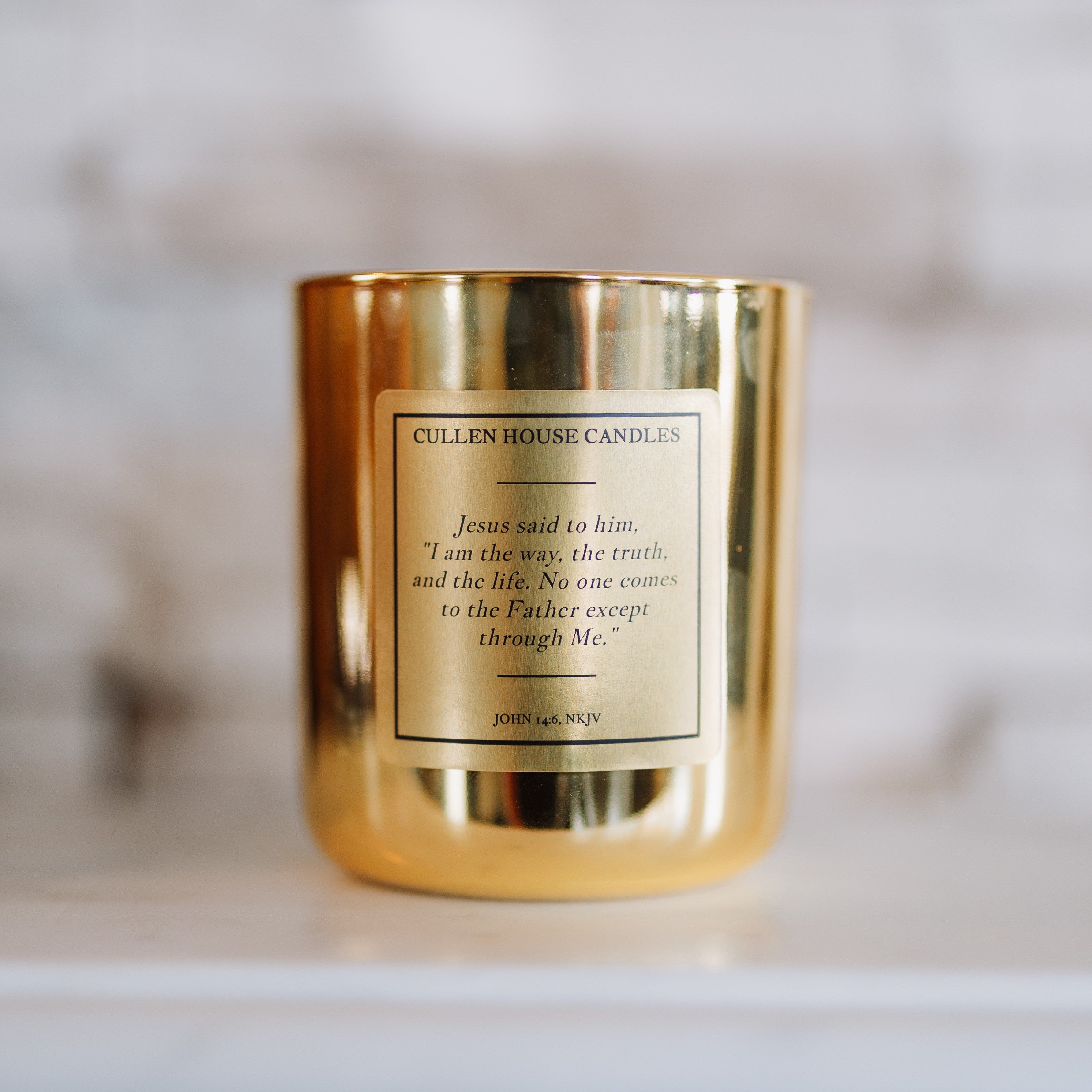 Gold candle with a label on a white surface