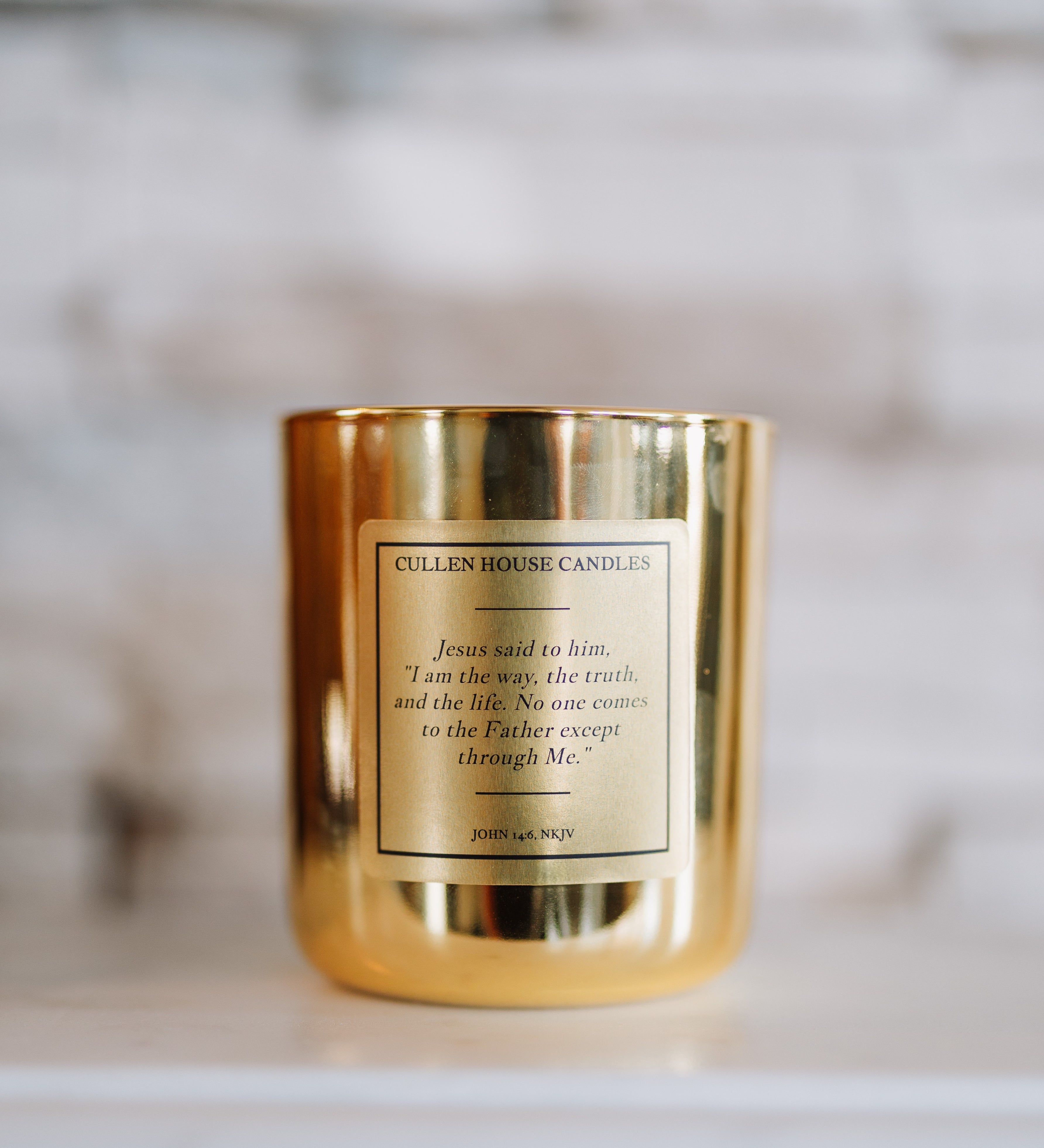 Gold candle with a label on a white surface