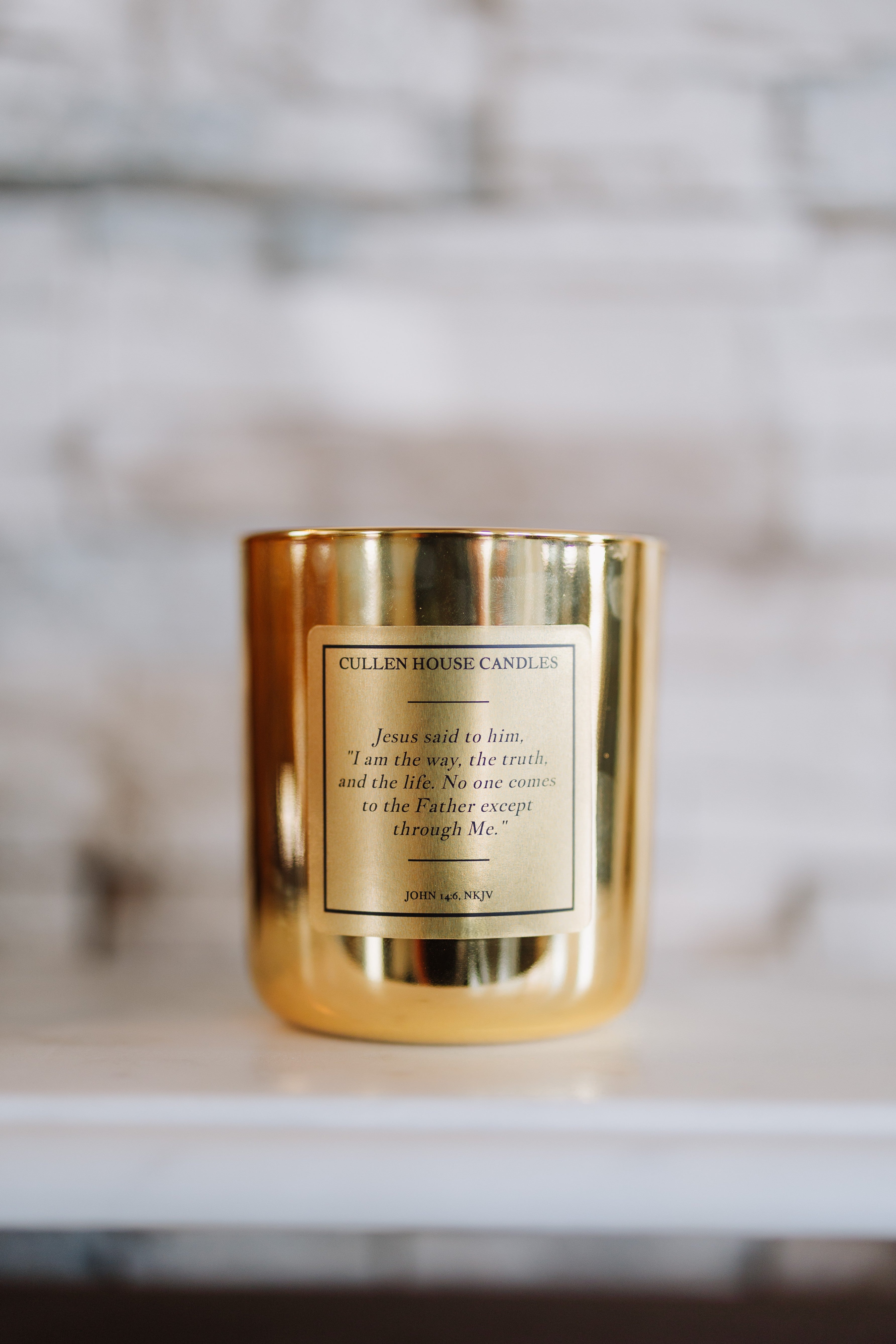 Gold candle with a label on a white surface