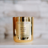 Gold candle with 'House of the Lord' label on a marble surface