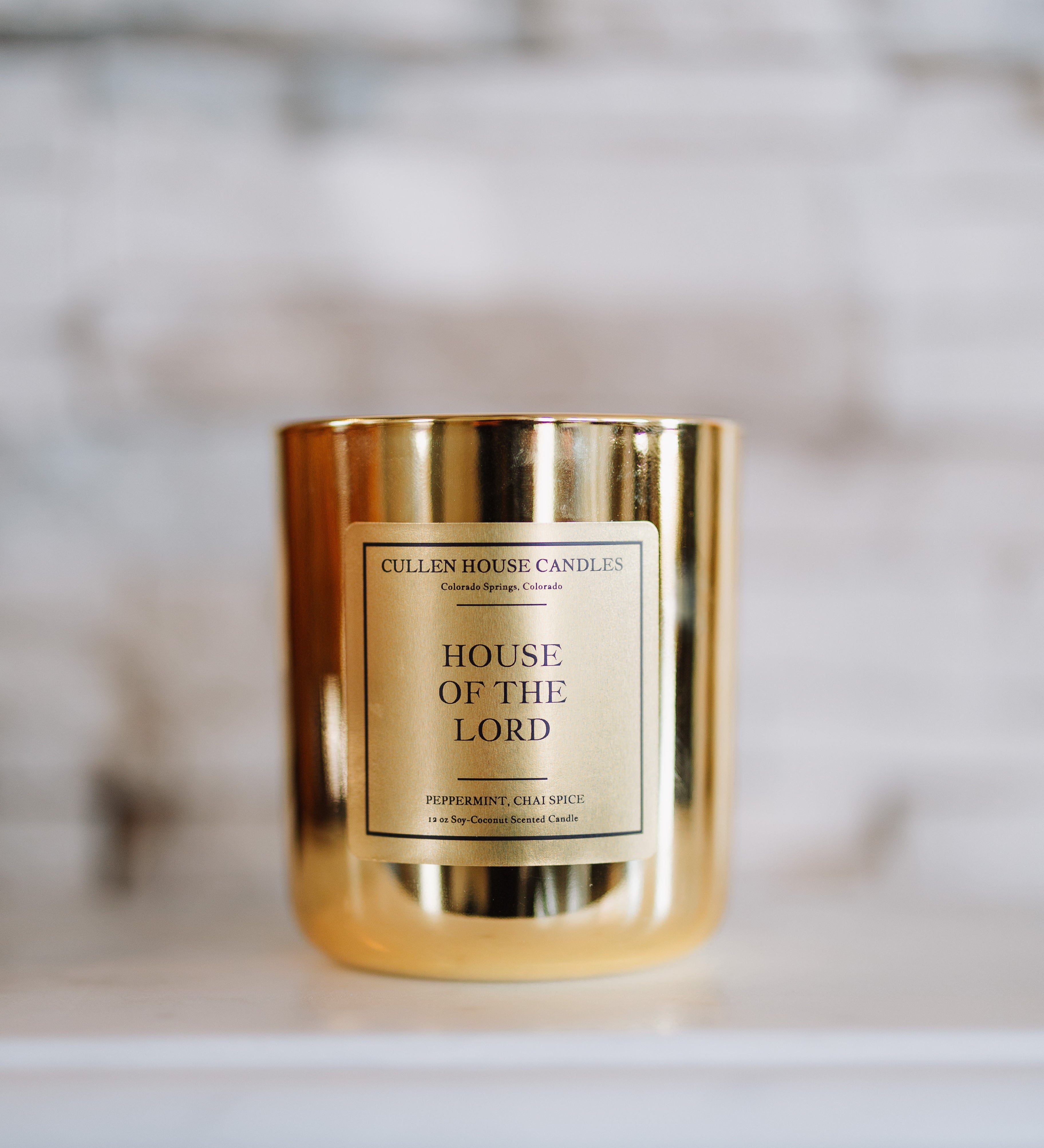 Gold candle with 'House of the Lord' label on a marble surface