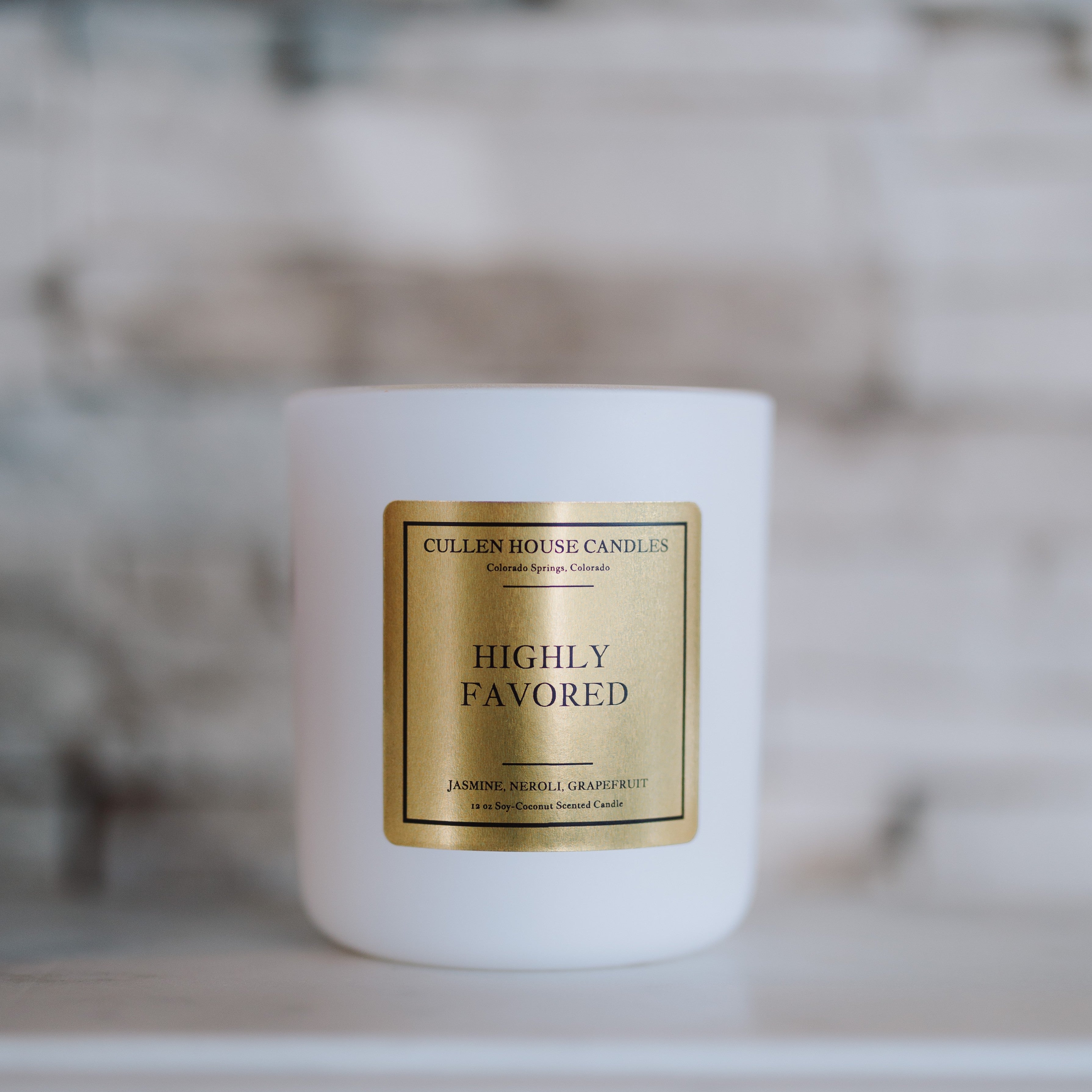 White candle with a gold label on a blurred background