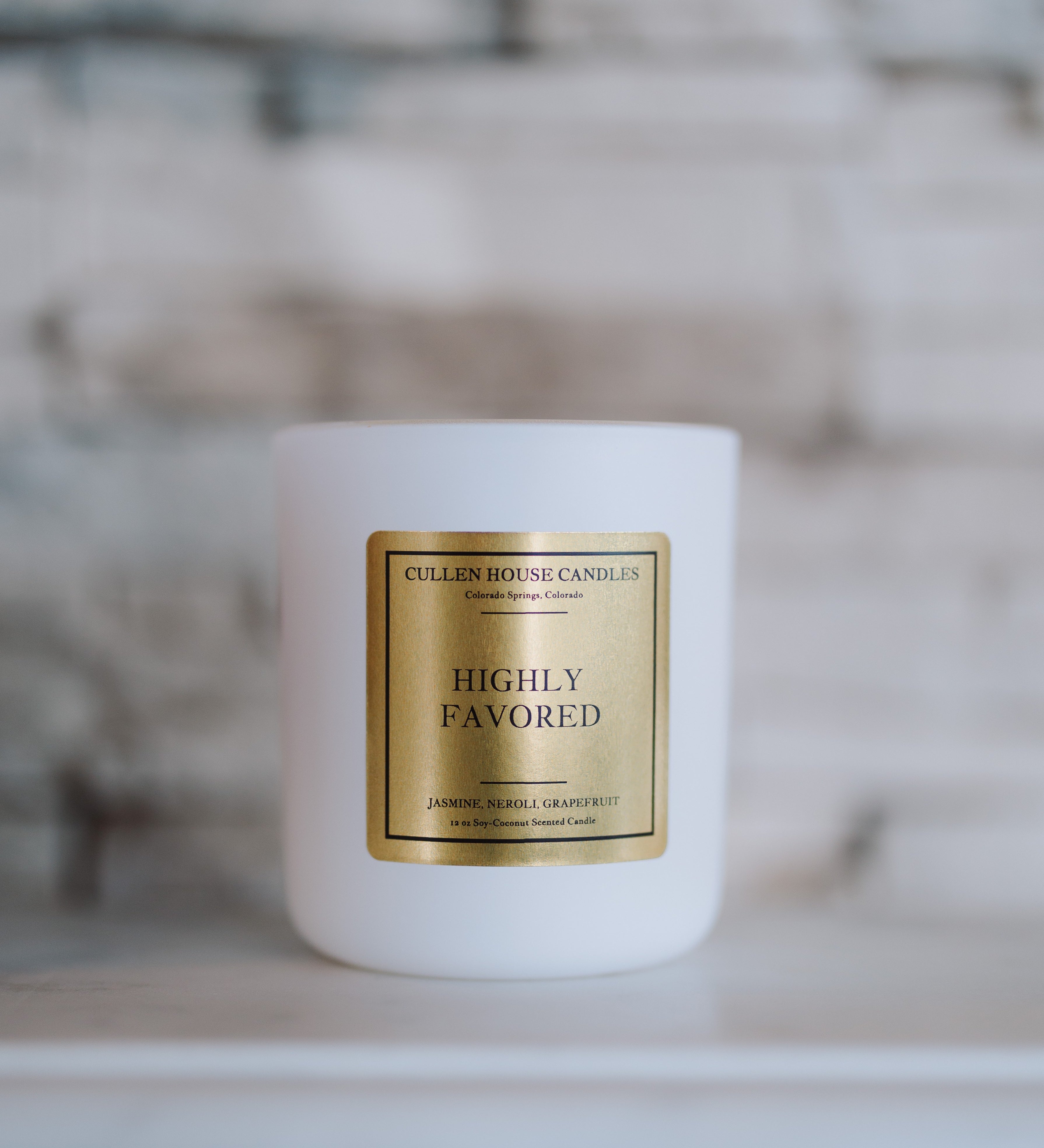 White candle with a gold label on a blurred background