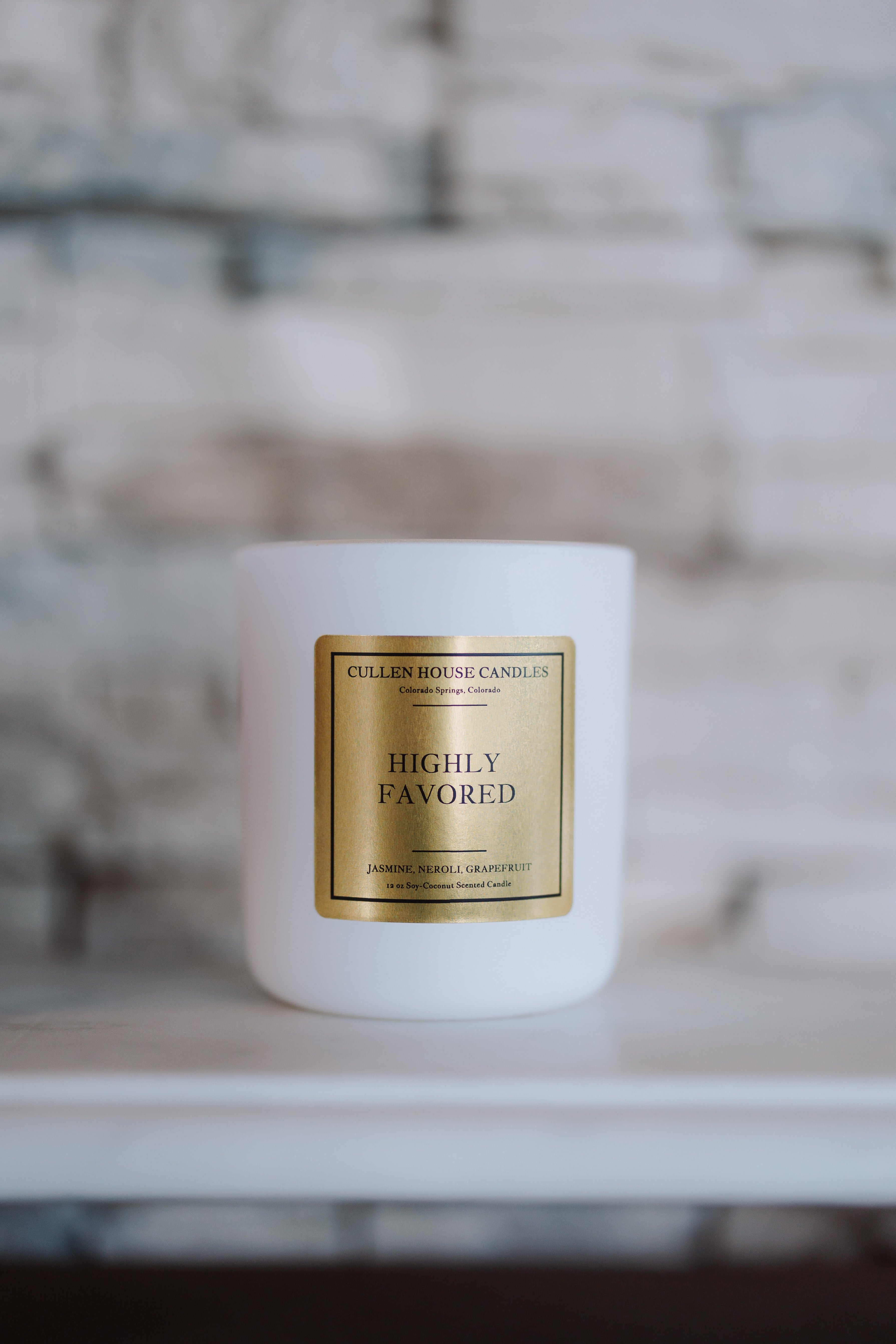 White candle with a gold label on a blurred background