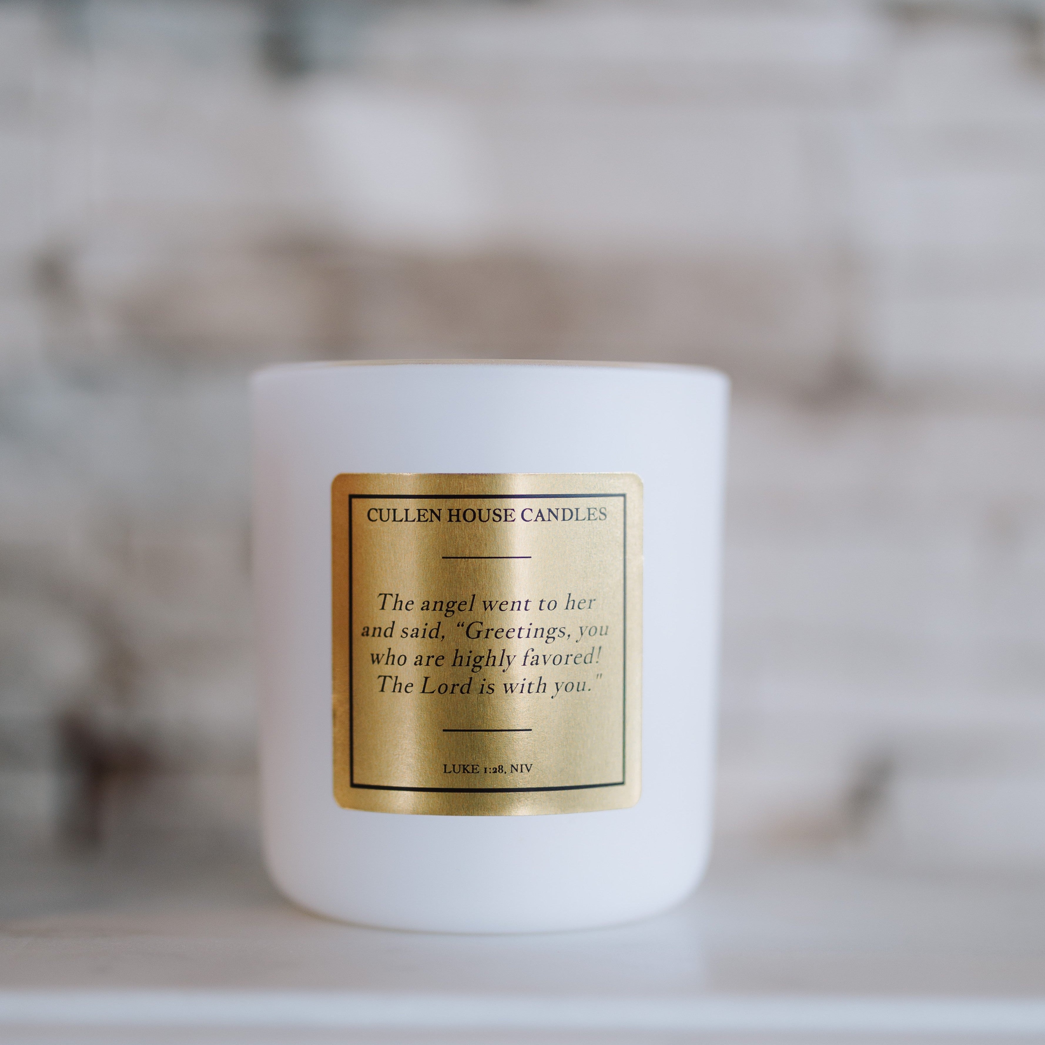 White candle with a gold label on a blurred background