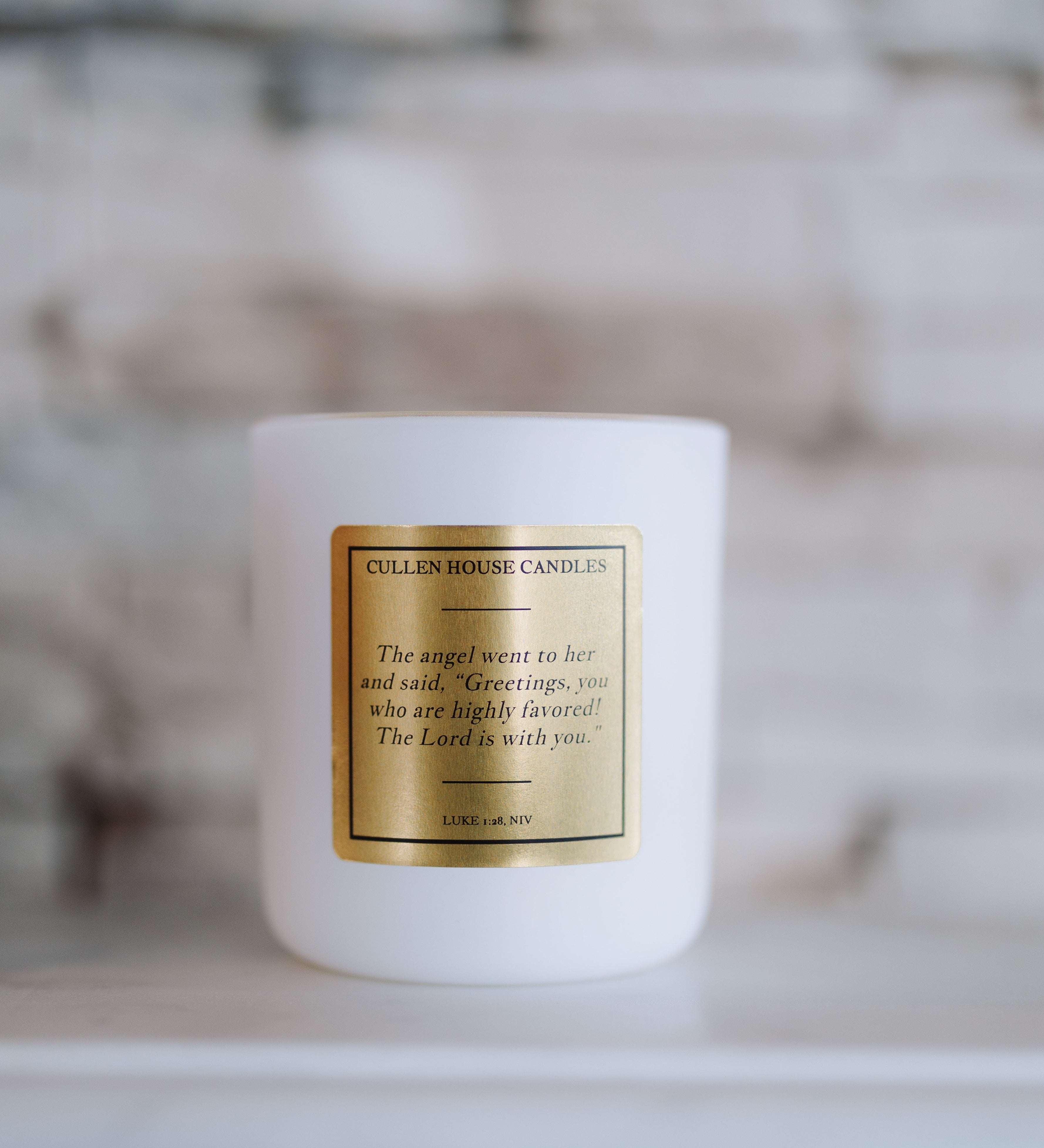 White candle with a gold label on a blurred background
