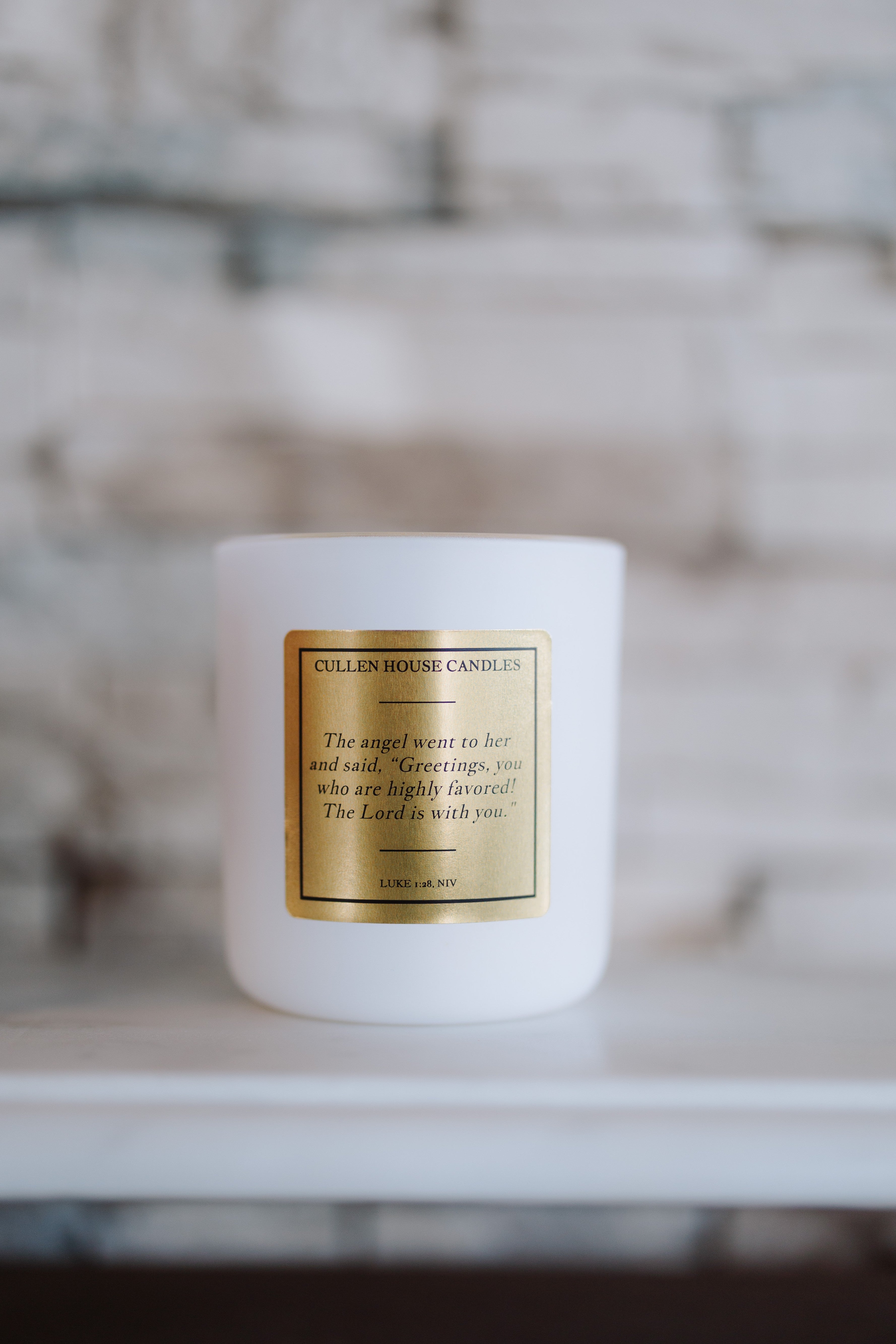 White candle with a gold label on a blurred background