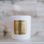 White candle with a gold label on a blurred background