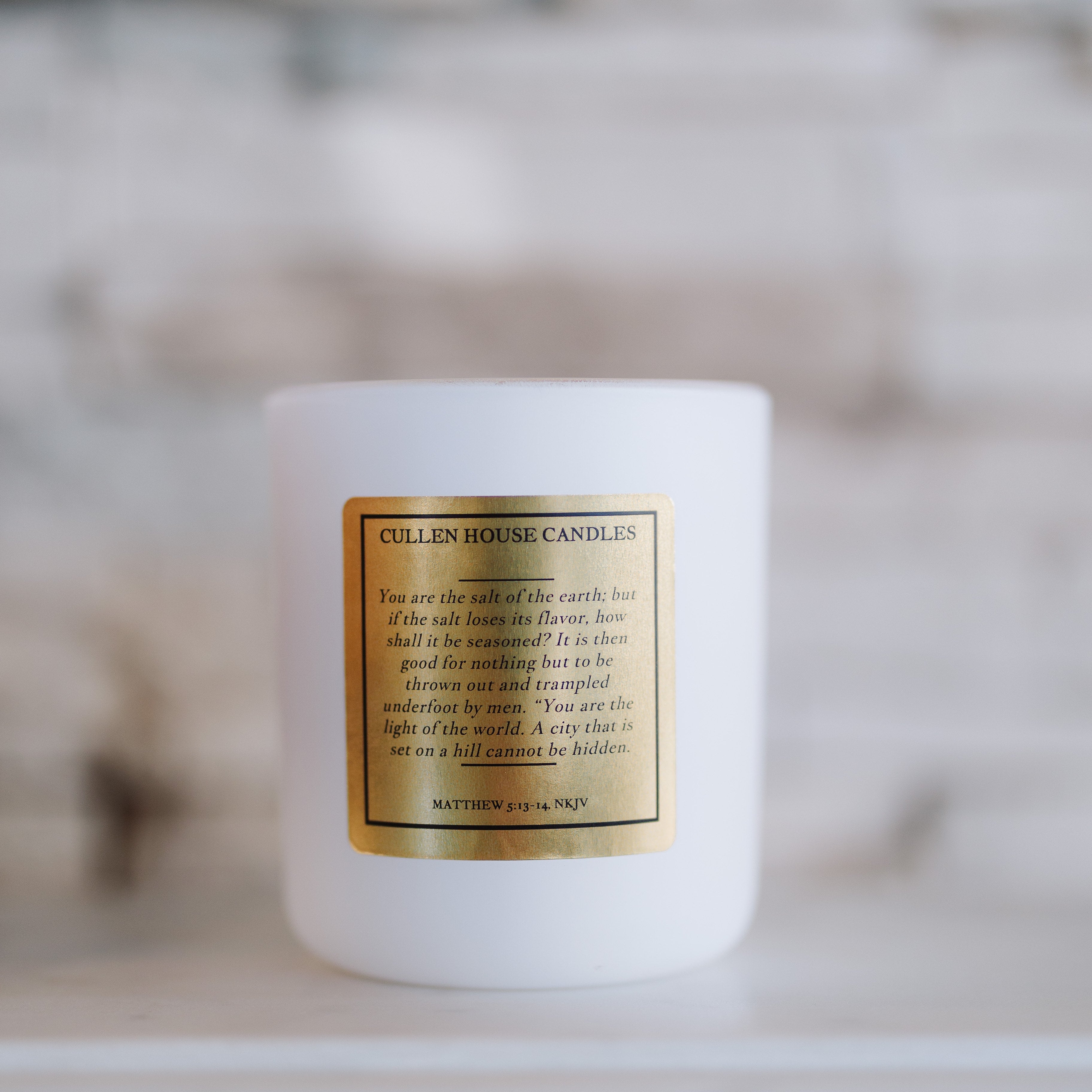 White candle with a gold label on a blurred background