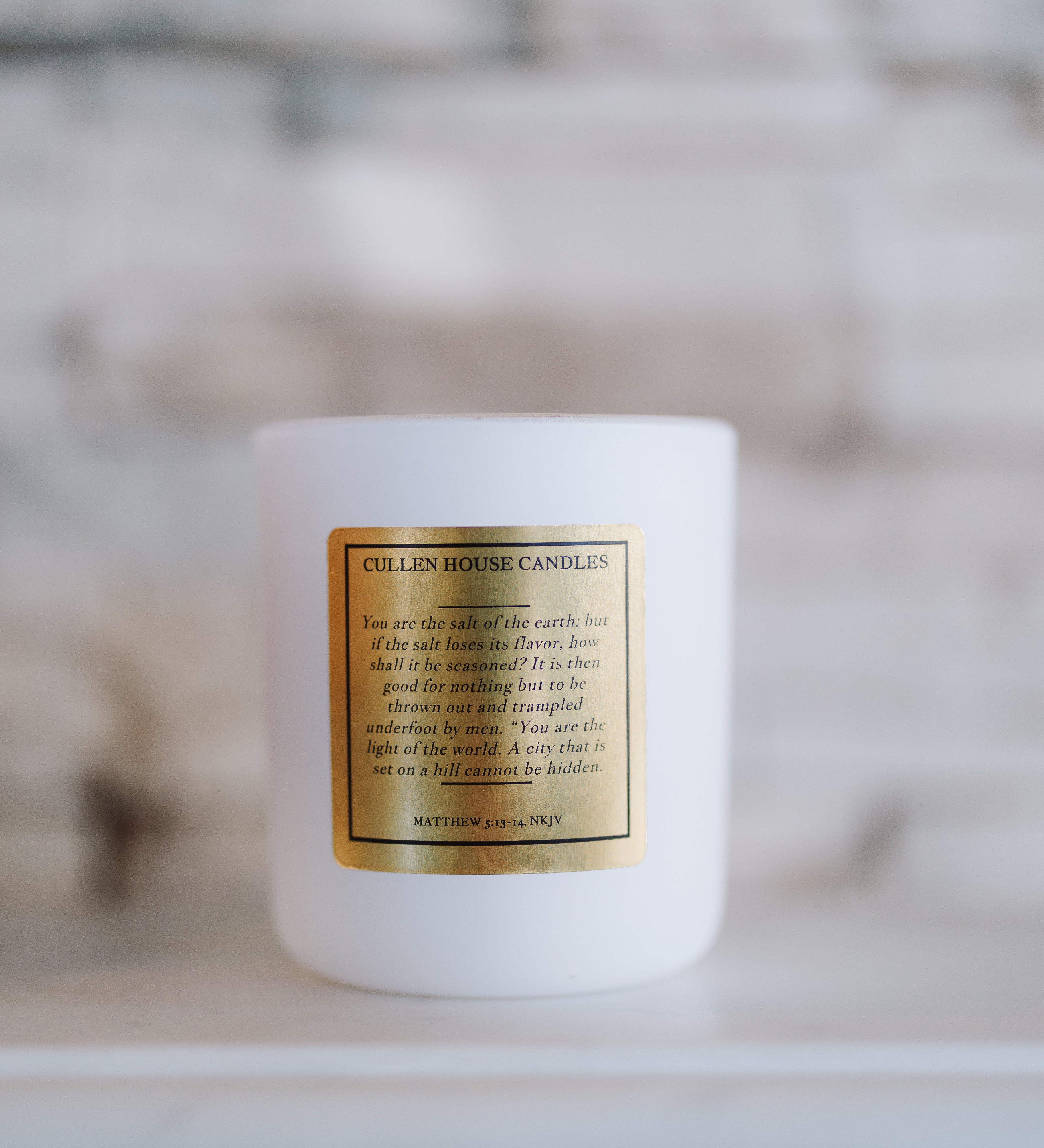 White candle with a gold label on a blurred background
