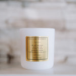 White candle with a gold label on a blurred background