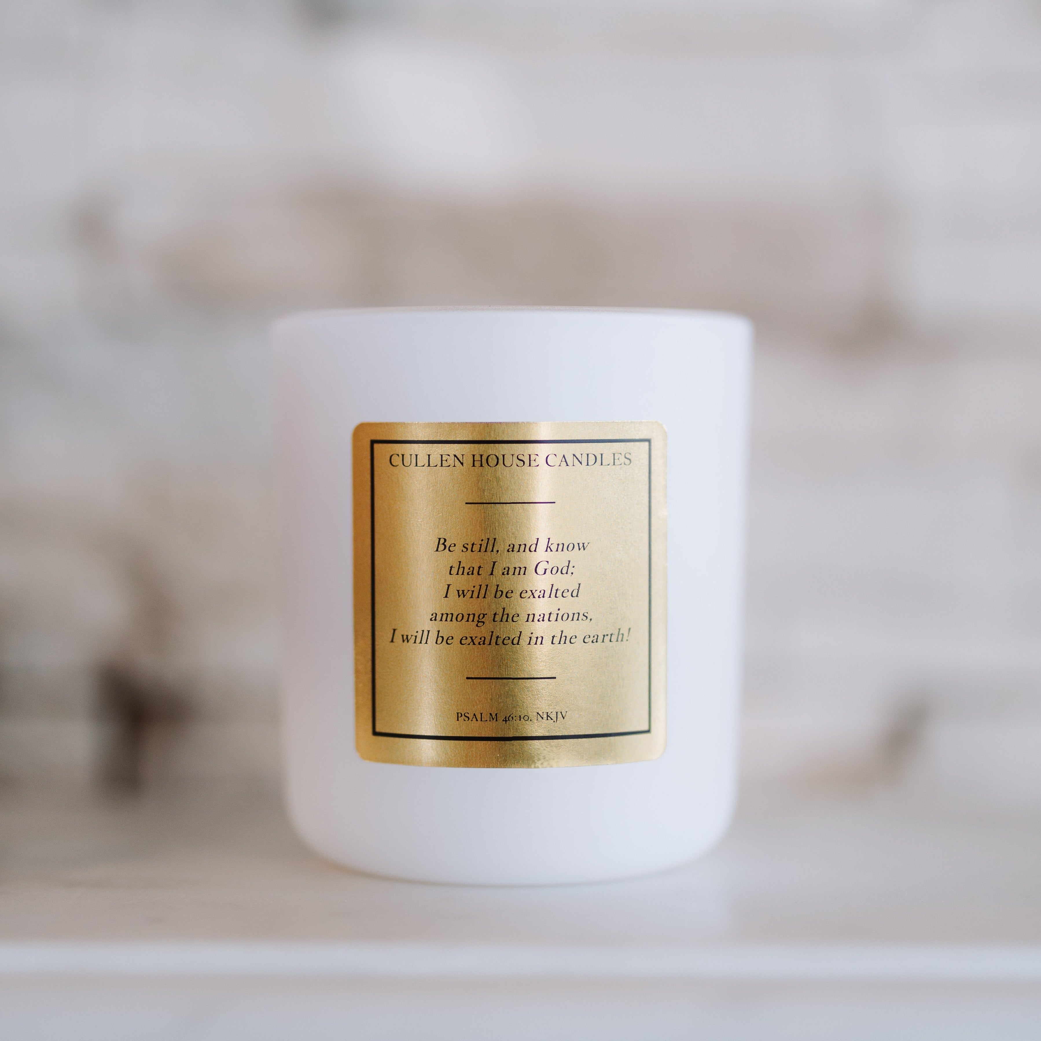 White candle with a gold label on a blurred background