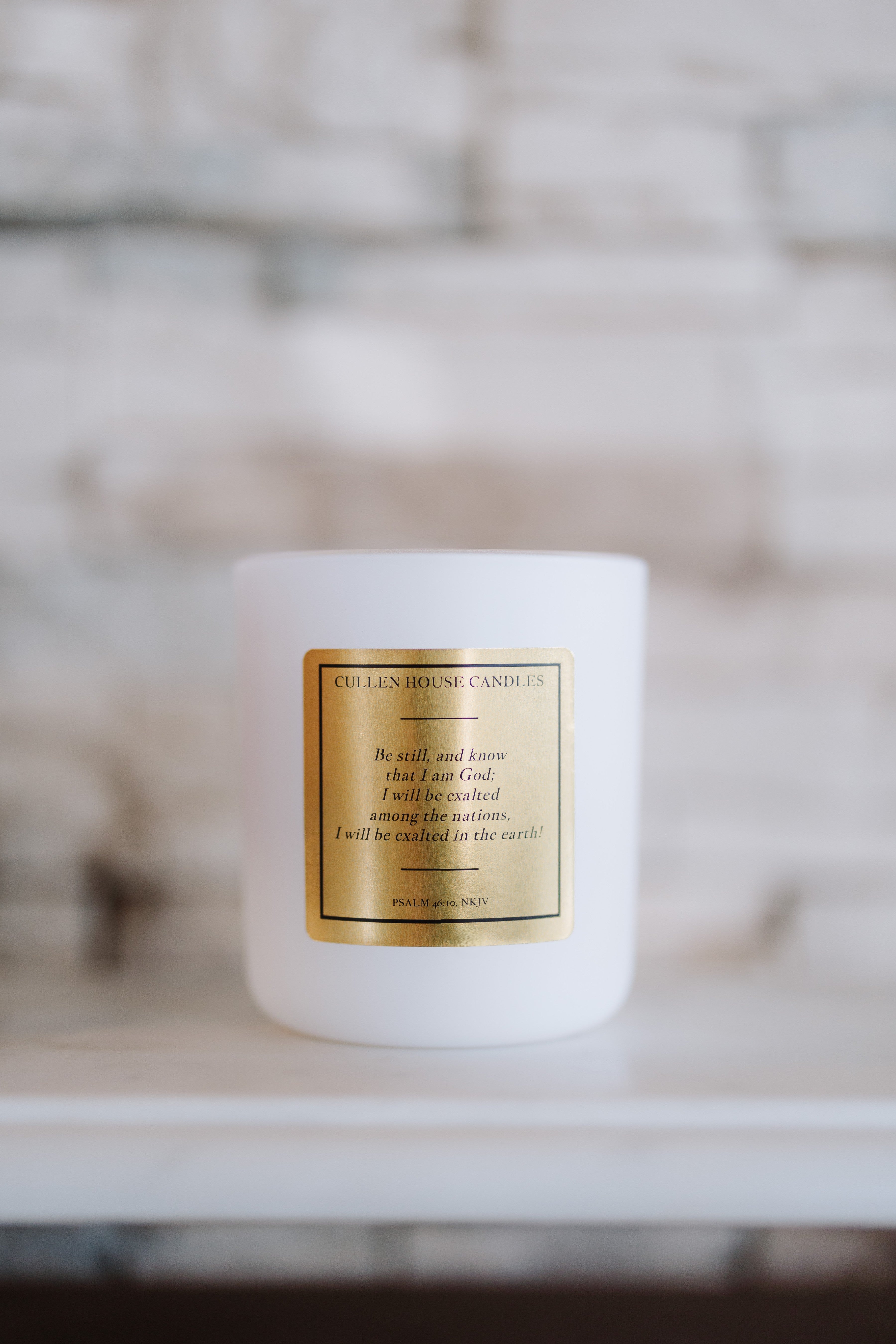 White candle with a gold label on a blurred background