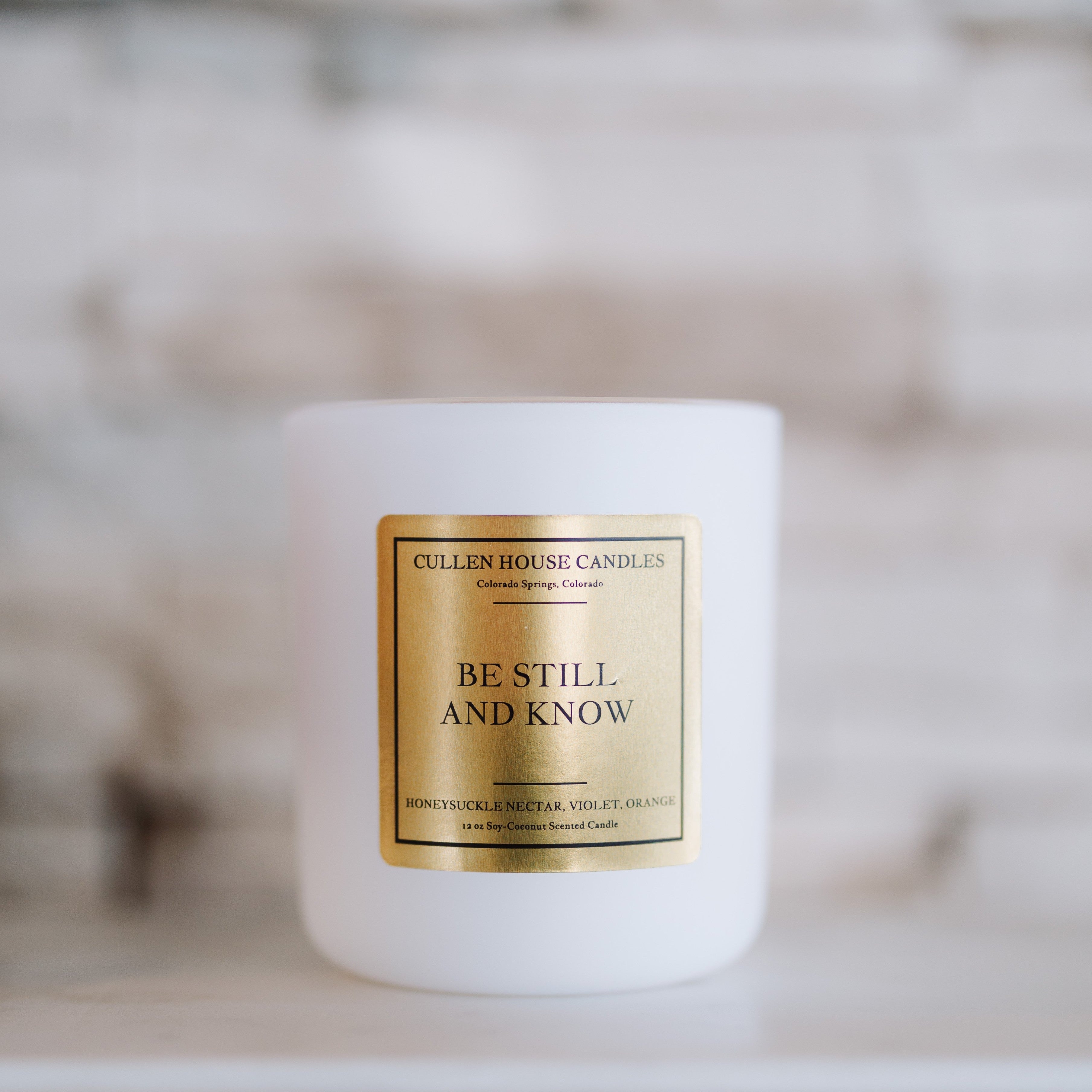 White candle with a gold label on a blurred background