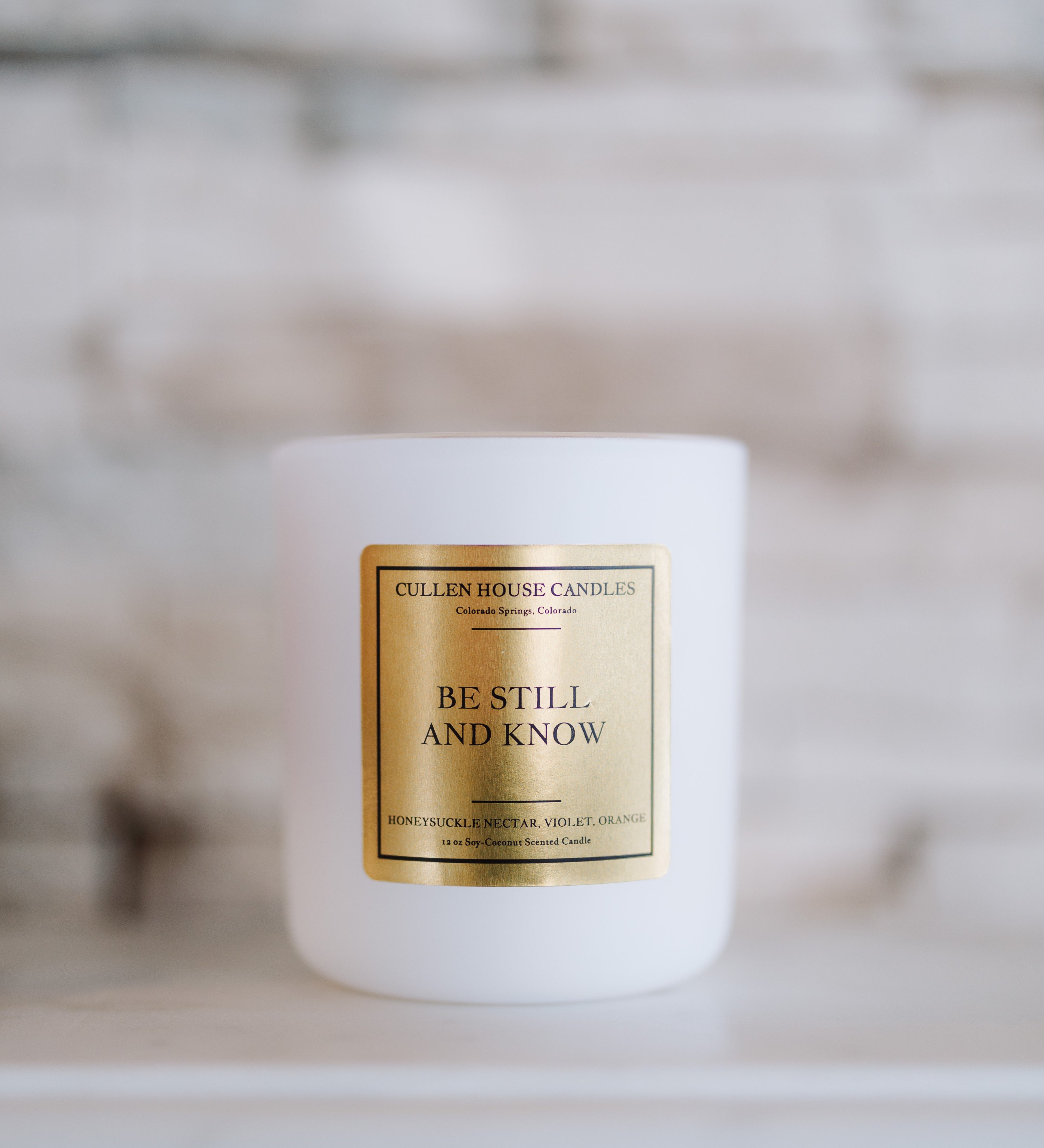 White candle with a gold label on a blurred background