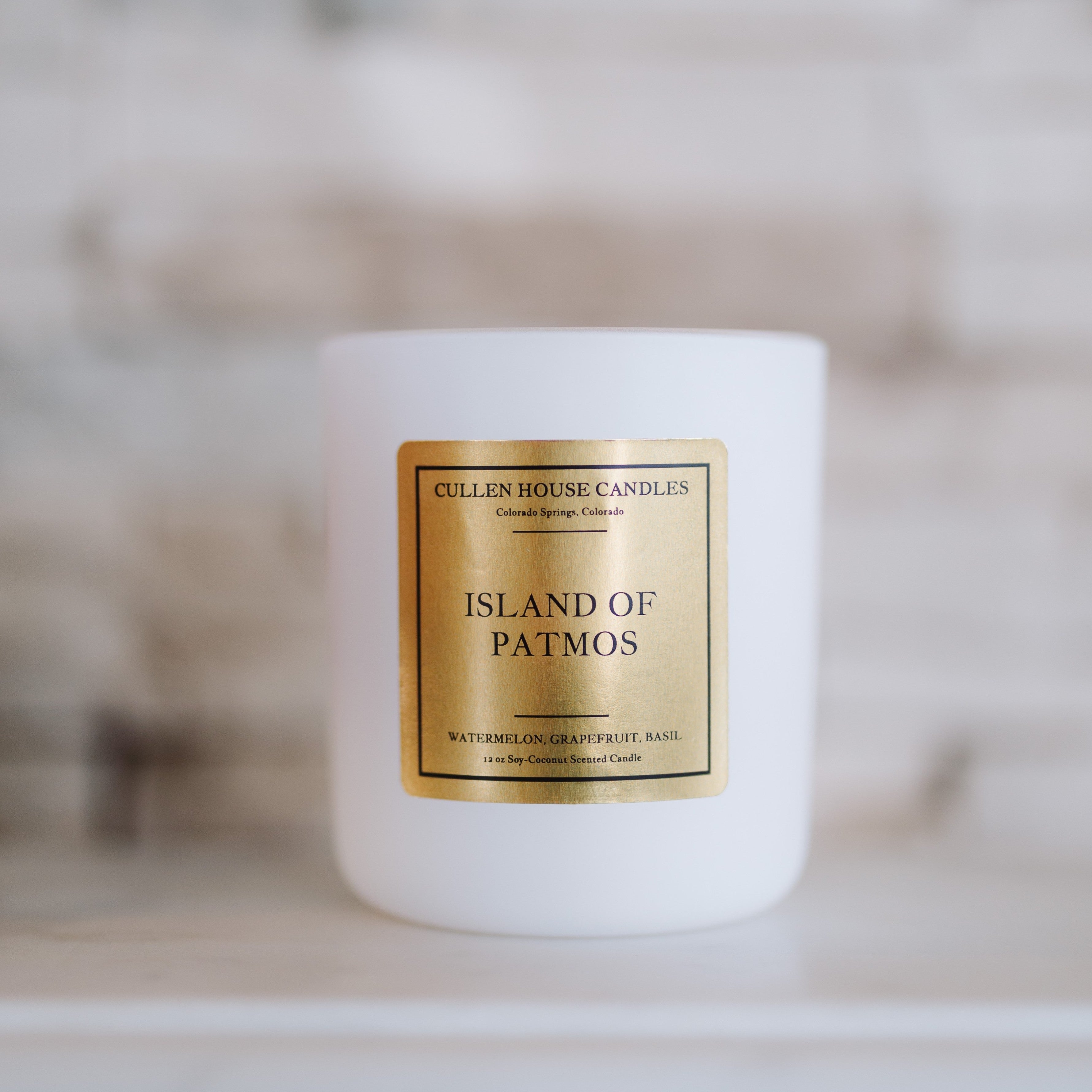 White candle with a gold label on a blurred background