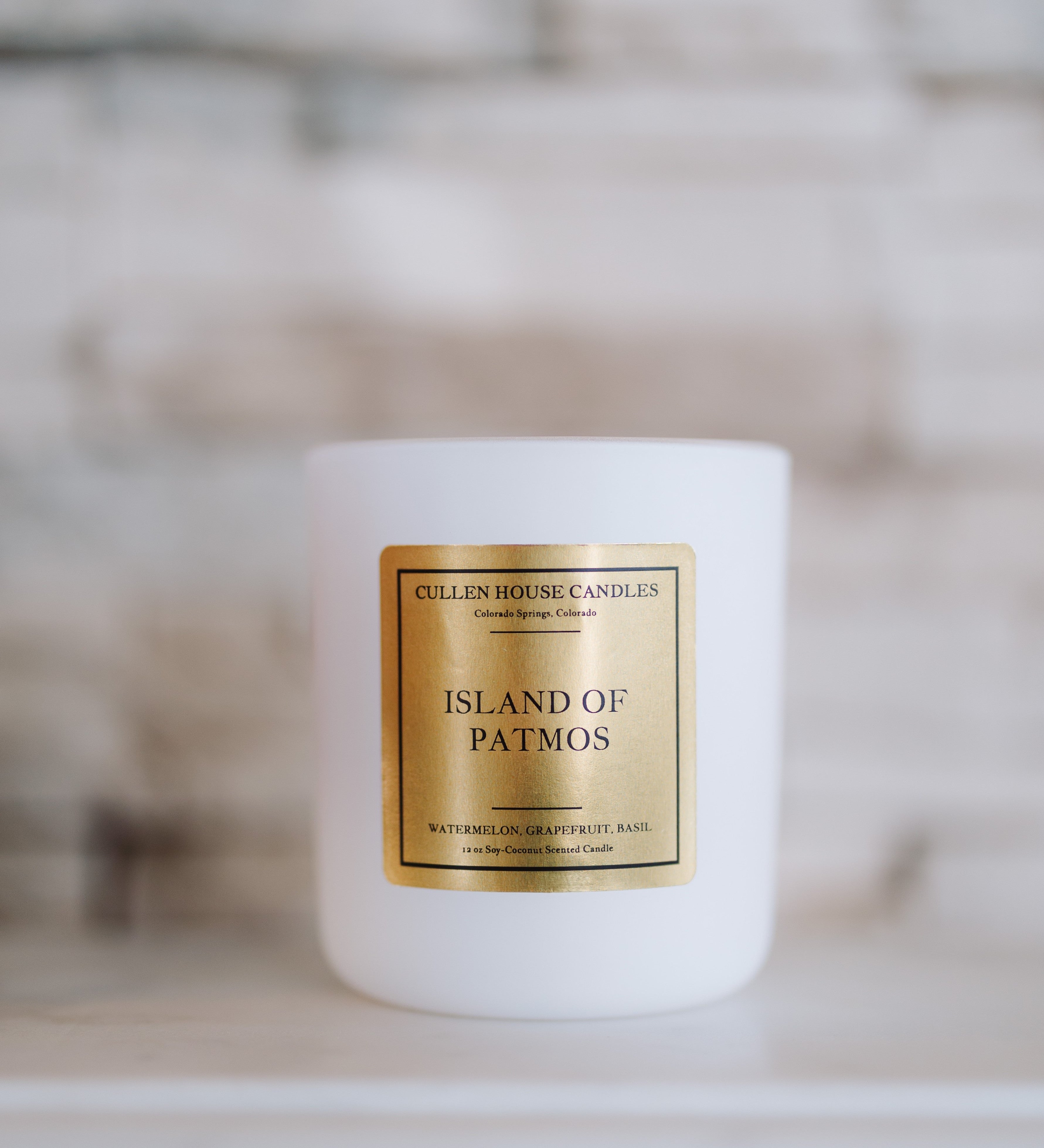 White candle with a gold label on a blurred background