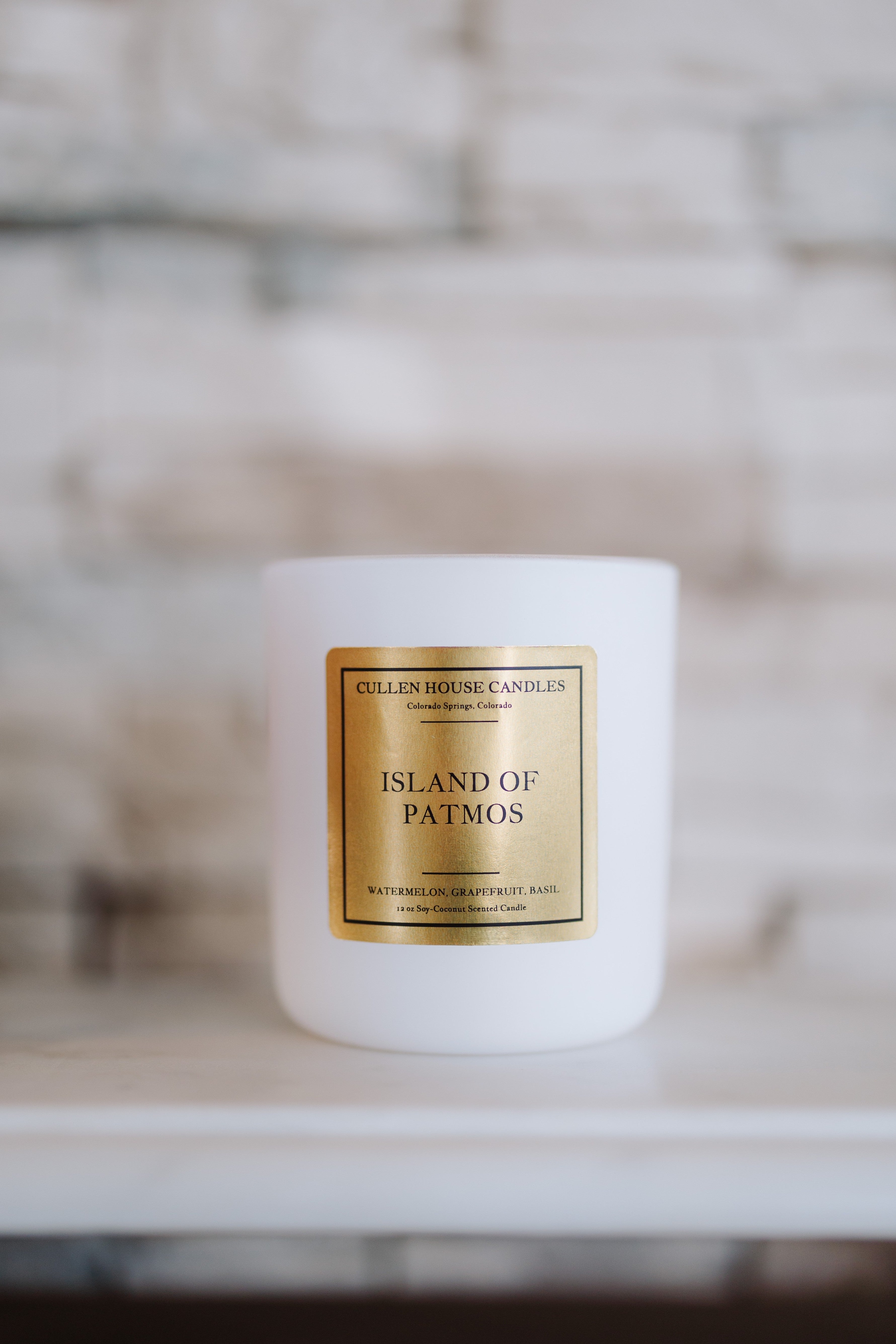 White candle with a gold label on a blurred background