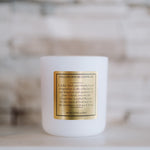 White candle with a gold label on a blurred background