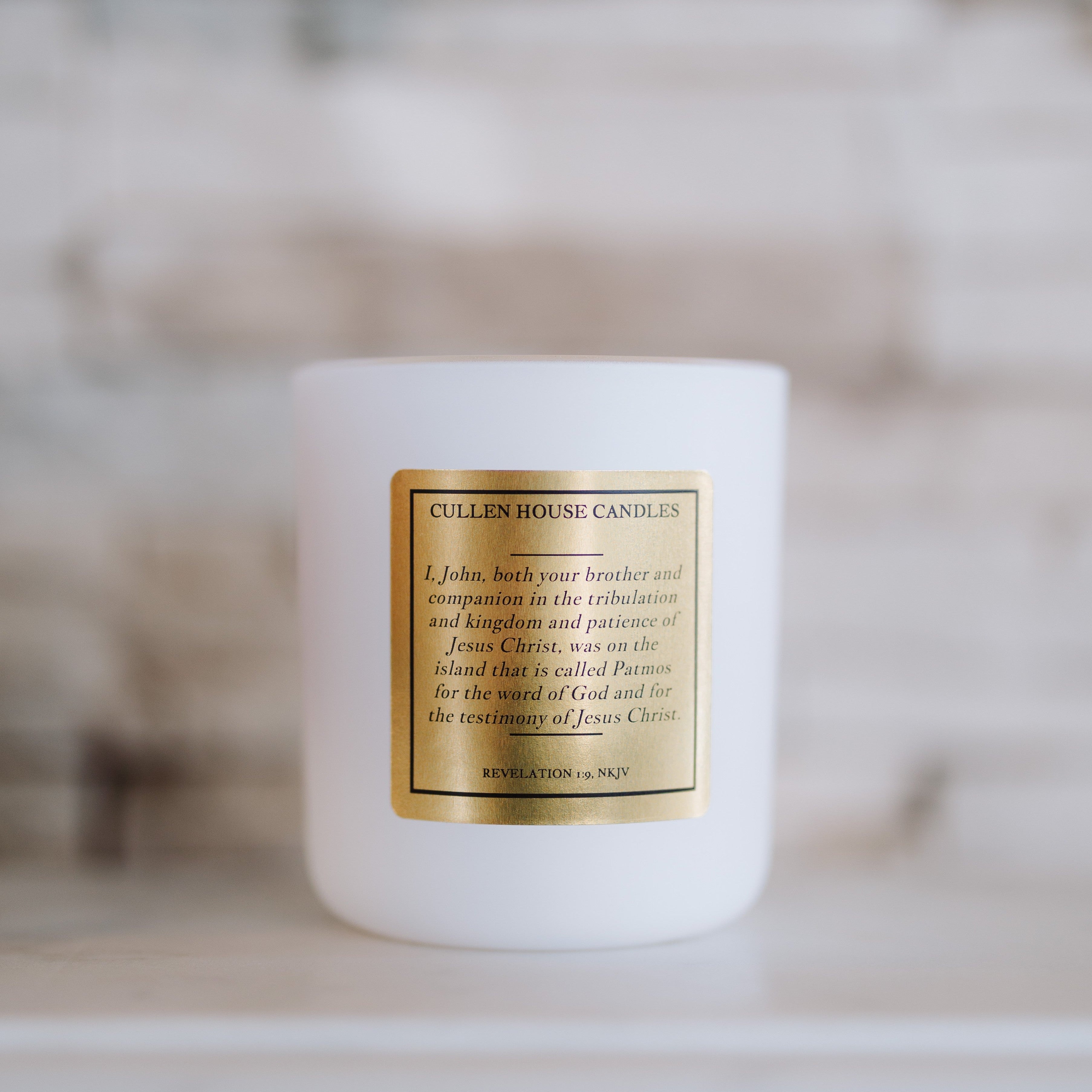 White candle with a gold label on a blurred background