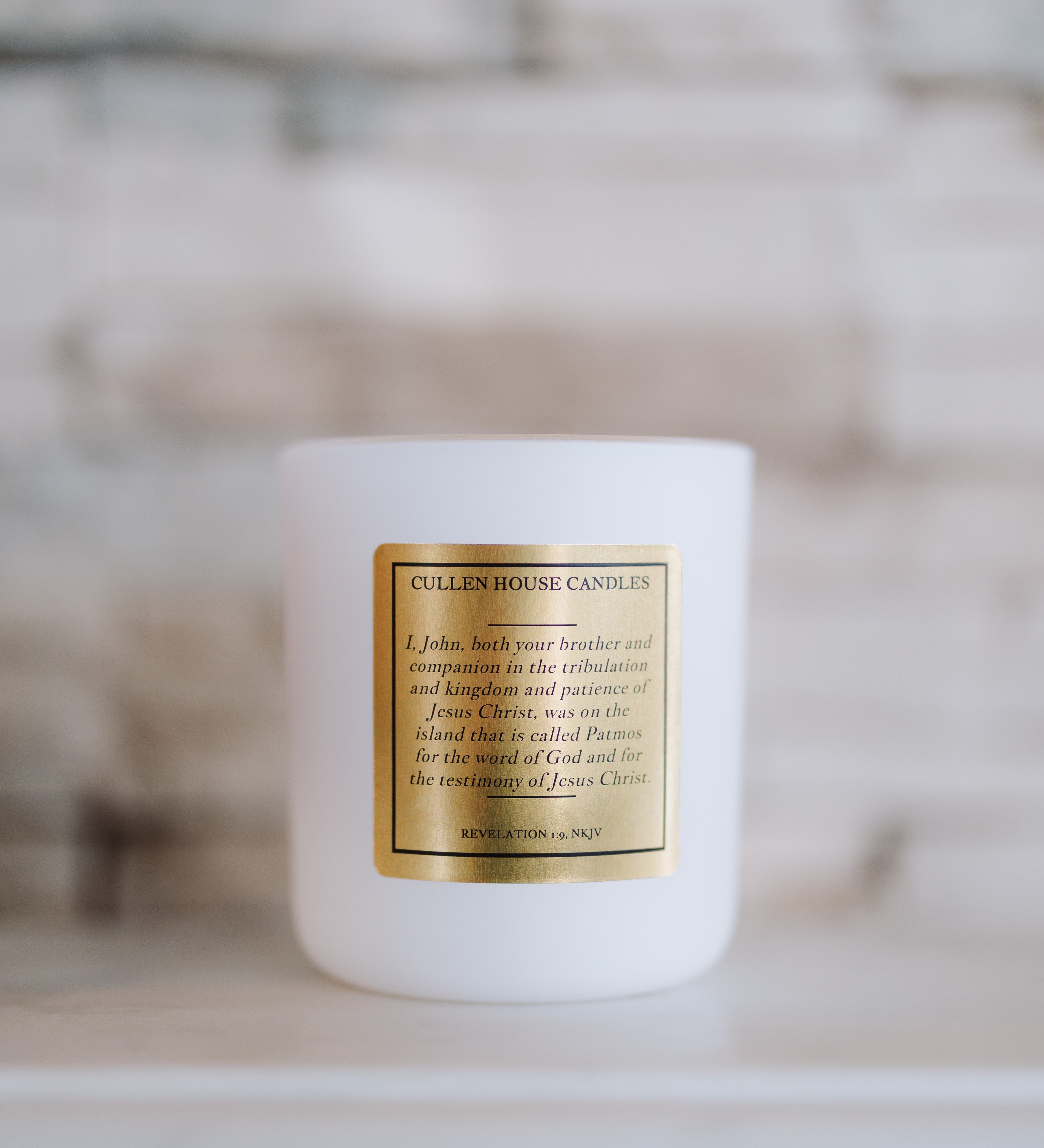White candle with a gold label on a blurred background
