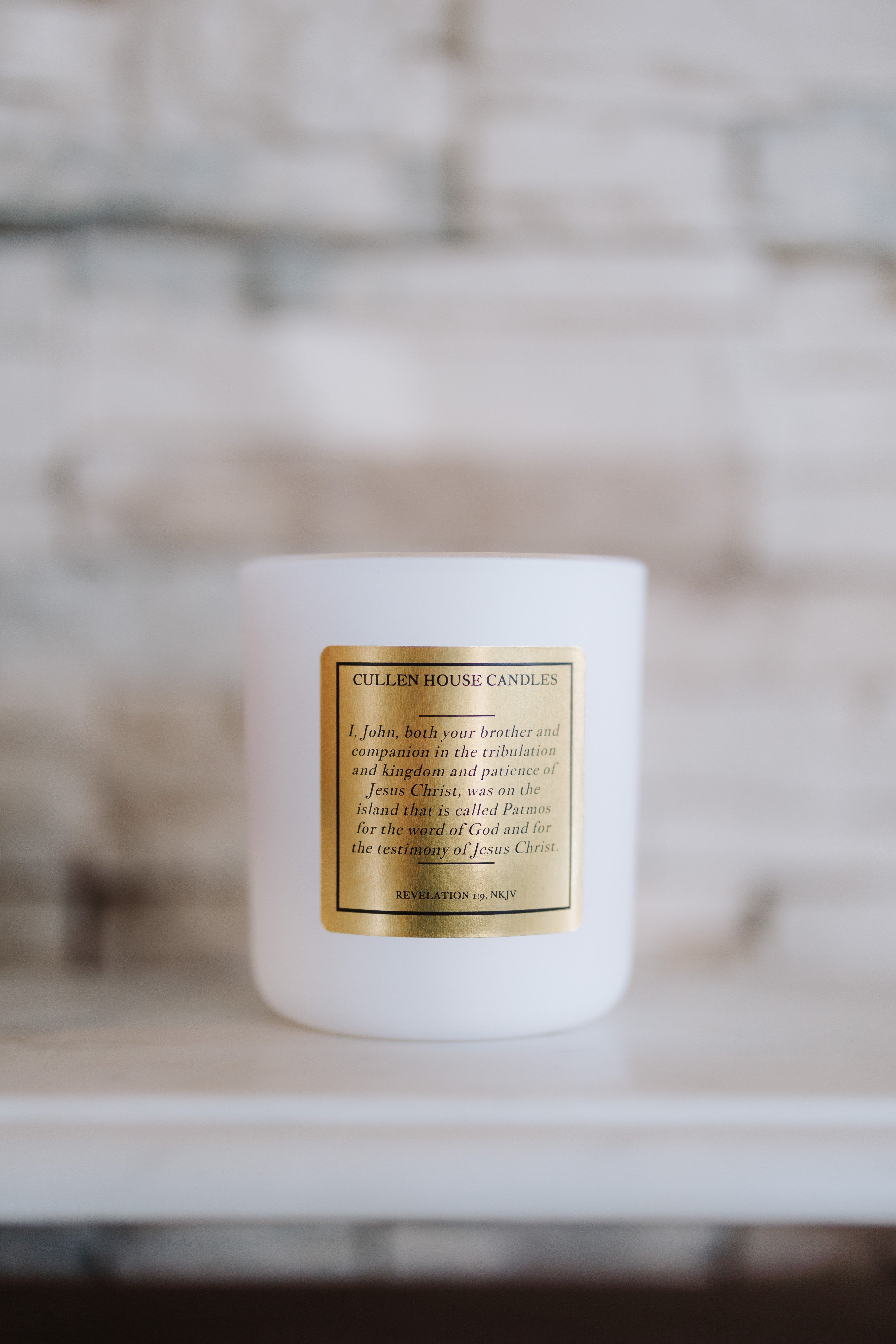 White candle with a gold label on a blurred background