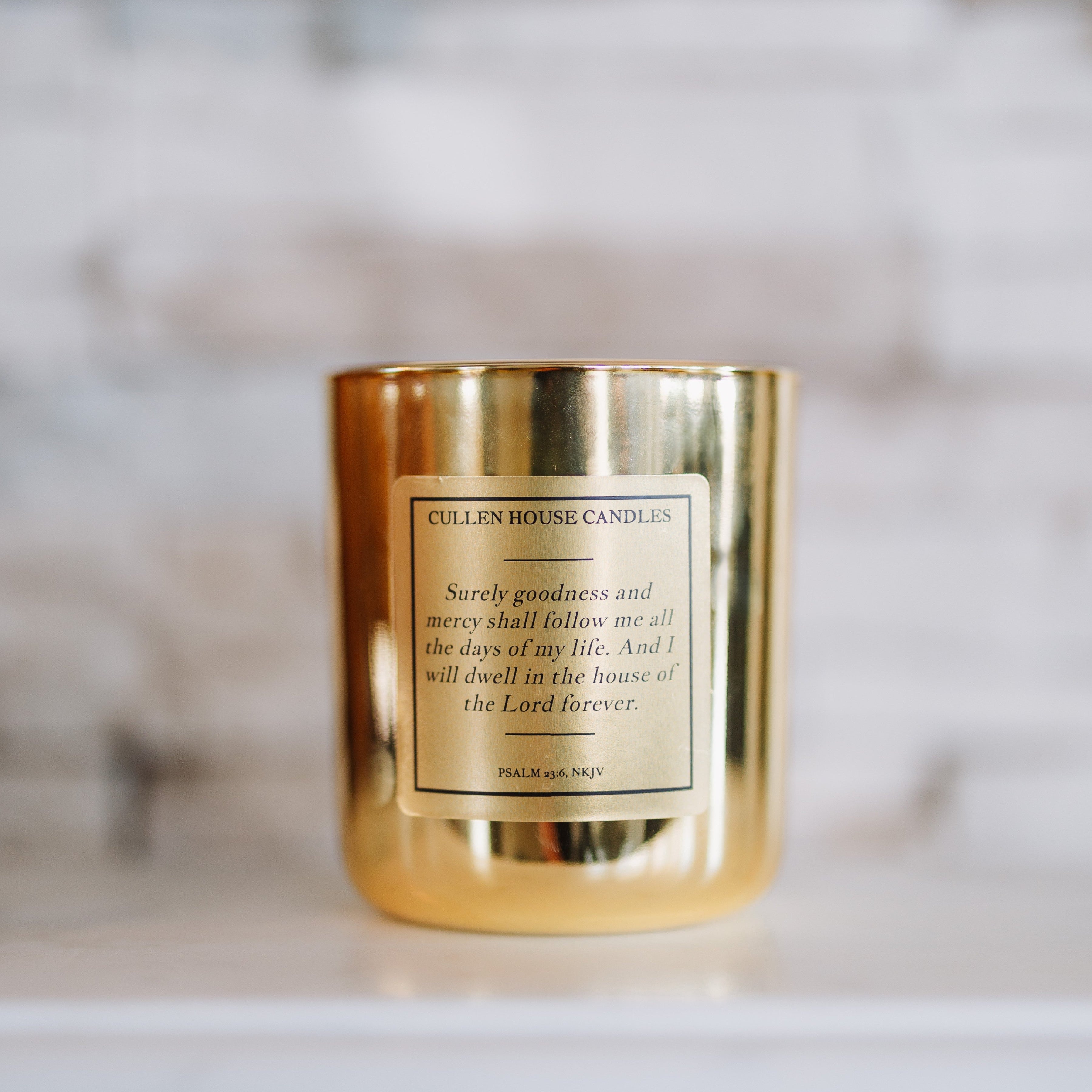 Gold candle with a label on a white surface