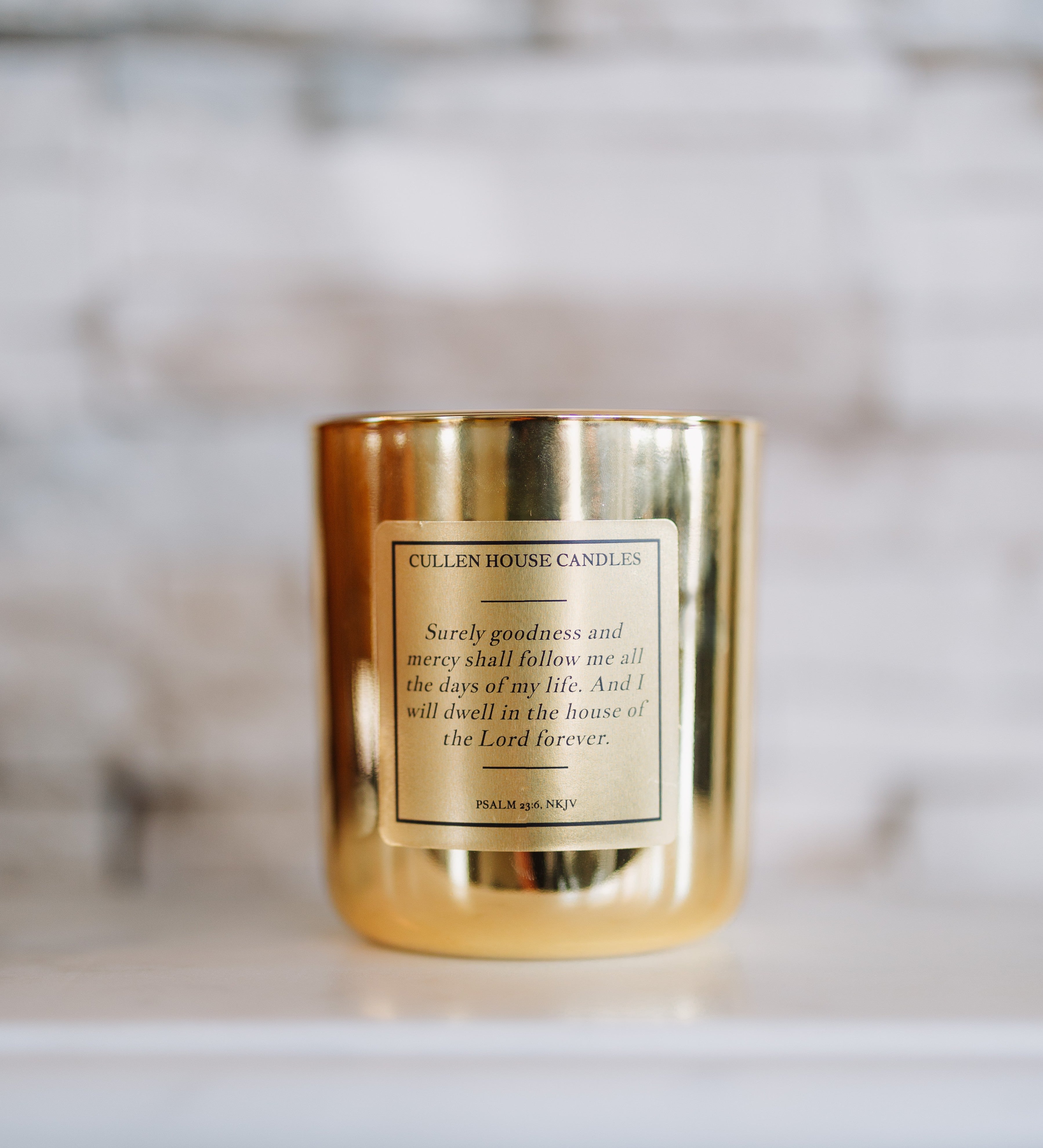 Gold candle with a label on a white surface