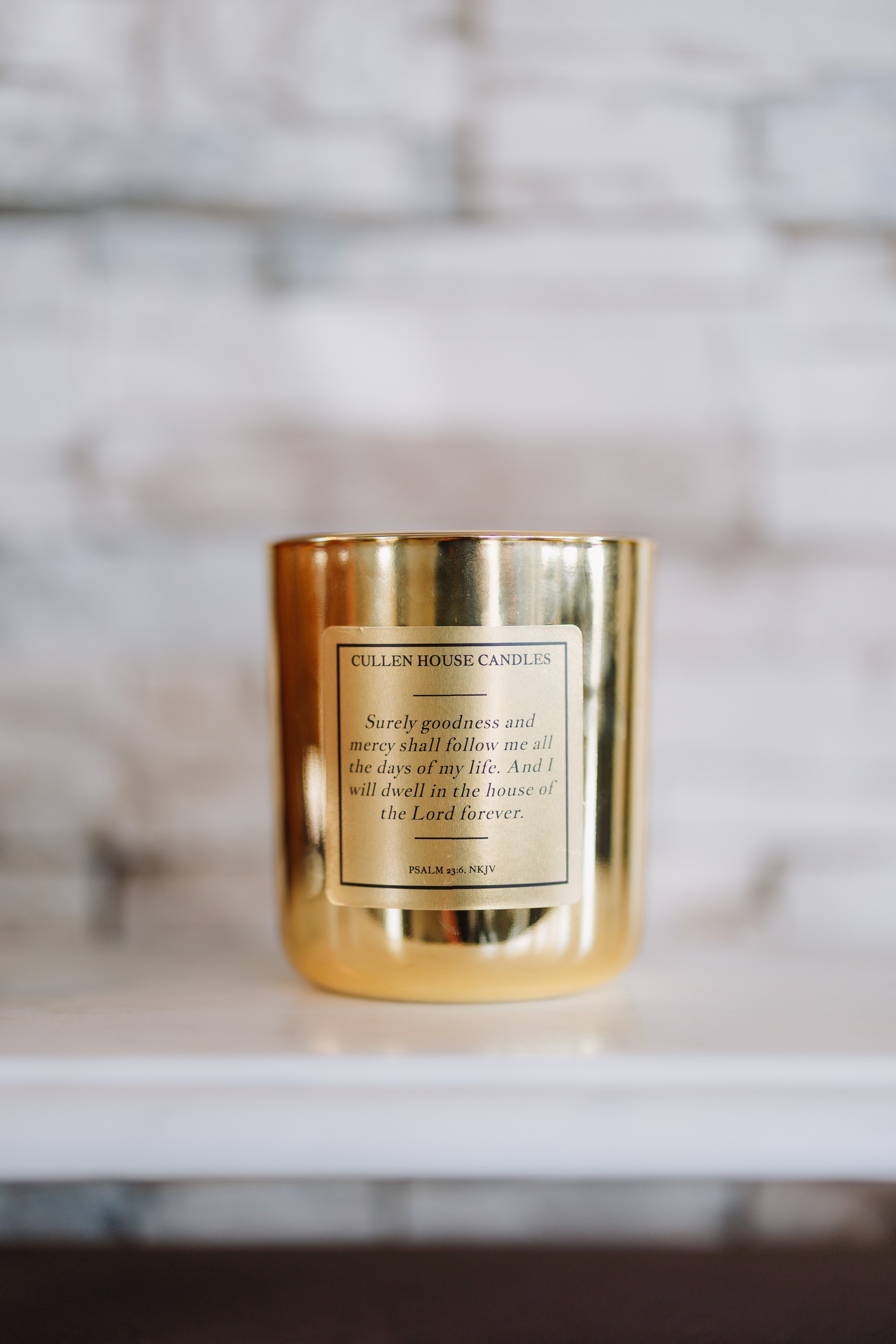 Gold candle with a label on a white surface