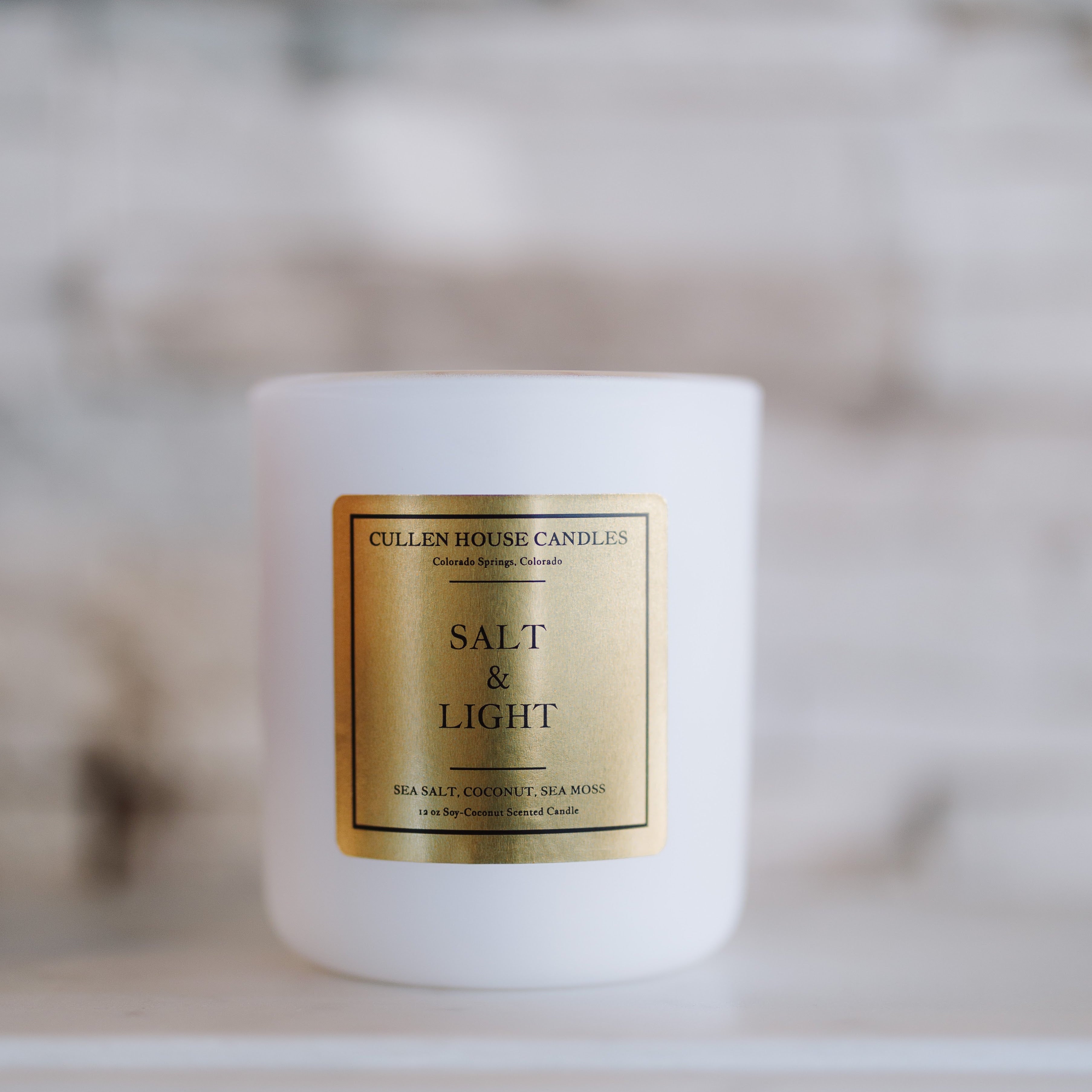 White candle with a gold label on a blurred background