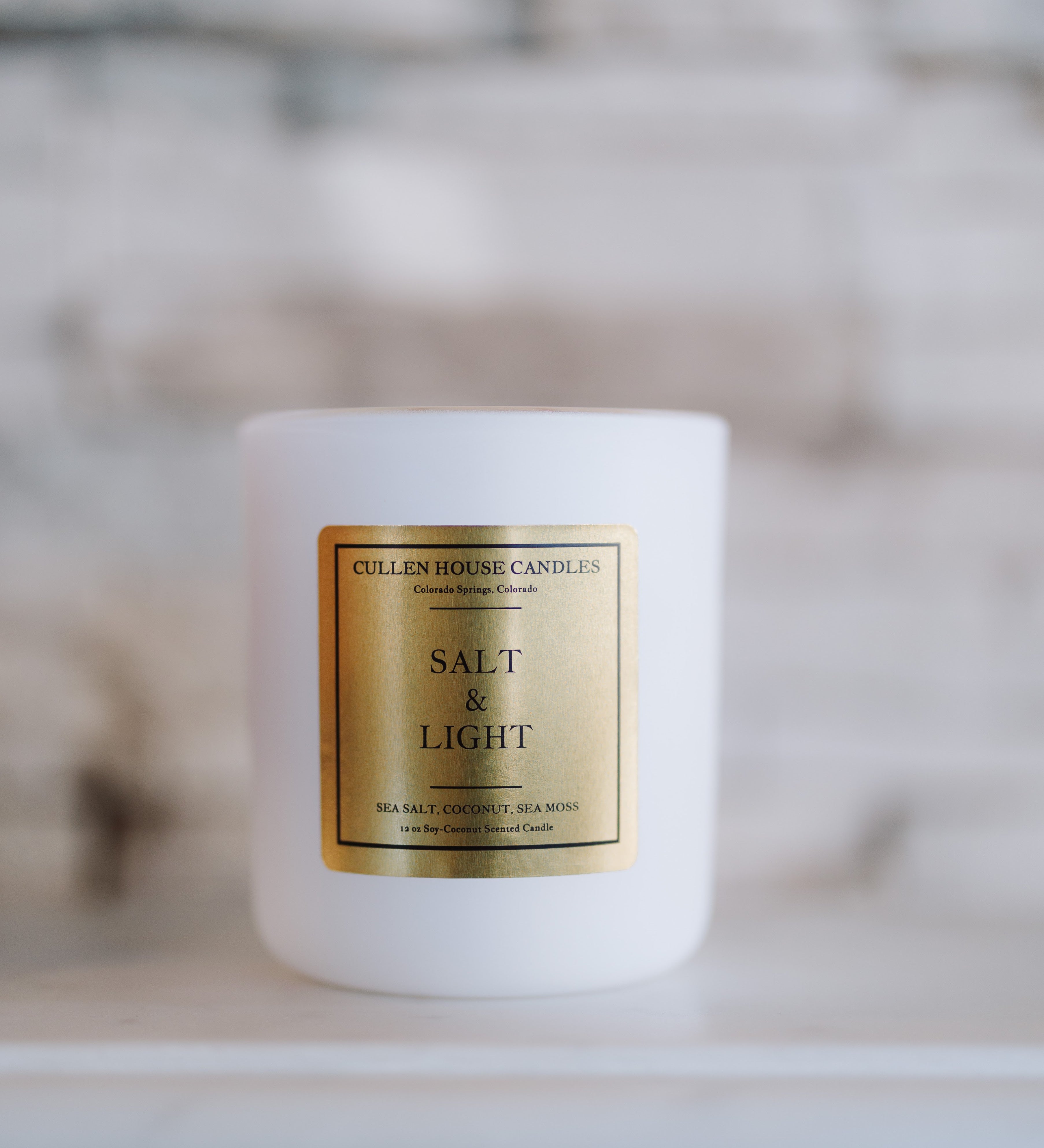 White candle with a gold label on a blurred background