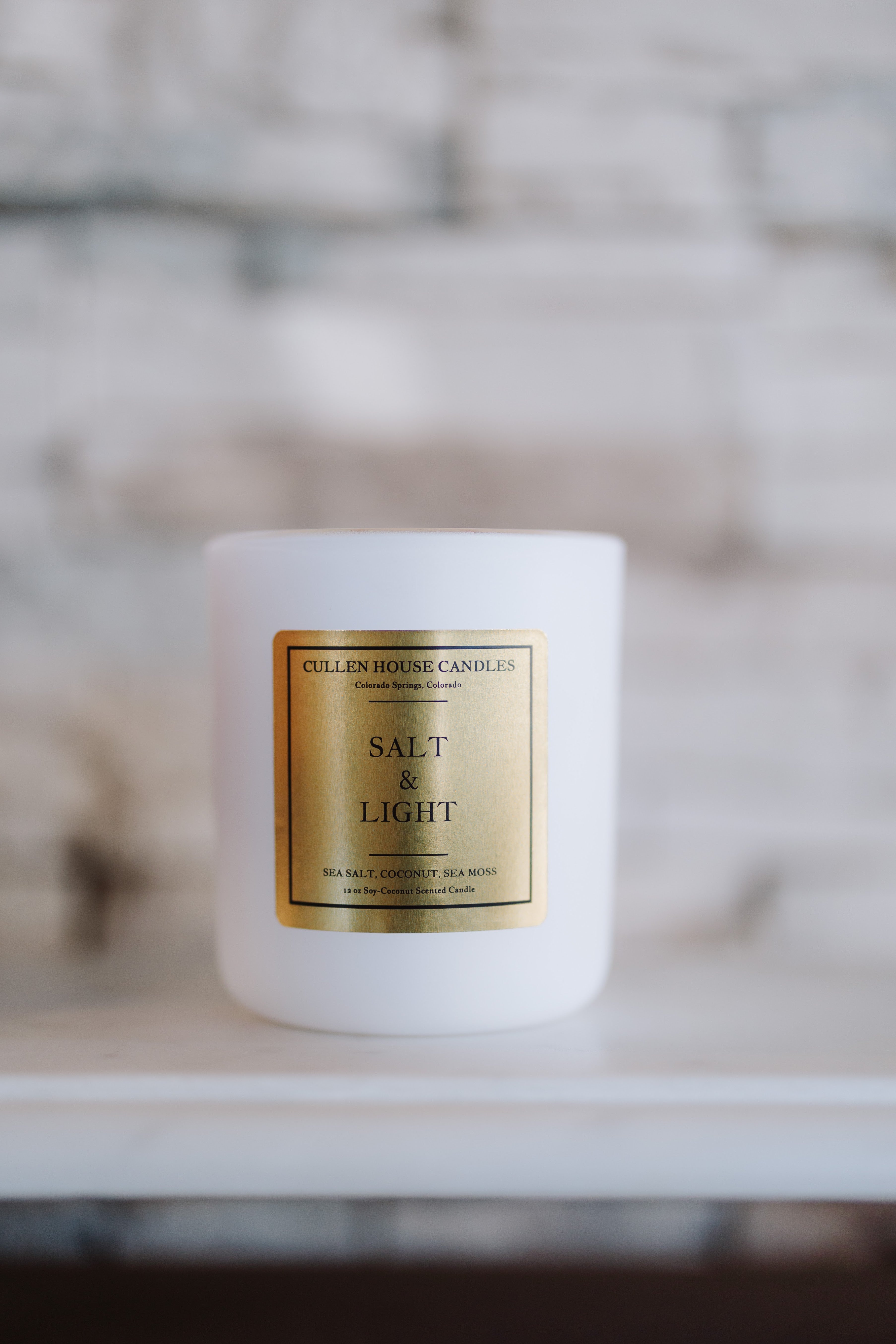 White candle with a gold label on a blurred background