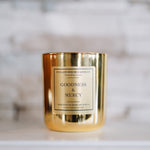 Gold candle with 'Goodness & Mercy' label on a marble surface