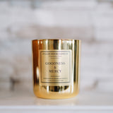 Gold candle with 'Goodness & Mercy' label on a marble surface