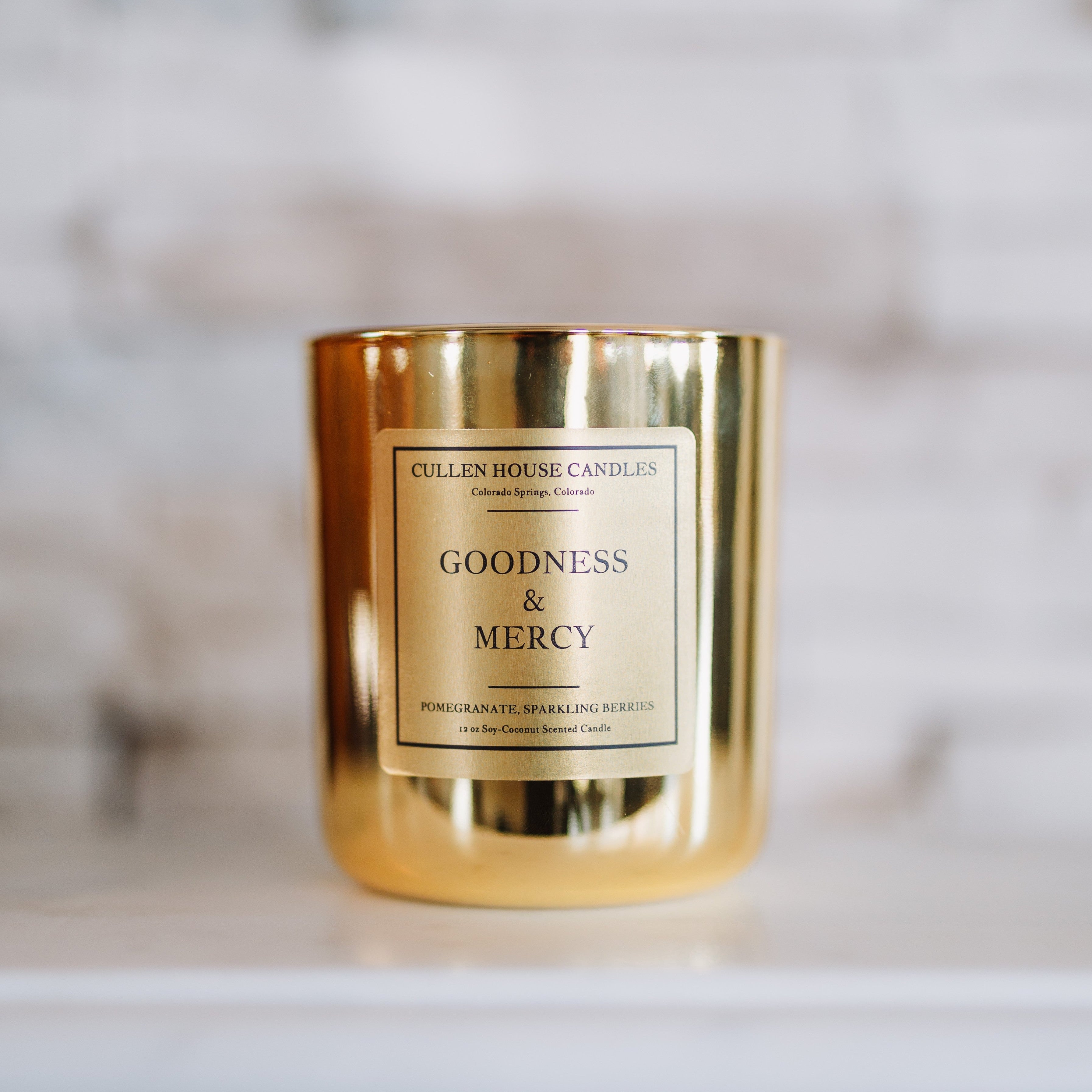Gold candle with 'Goodness & Mercy' label on a marble surface