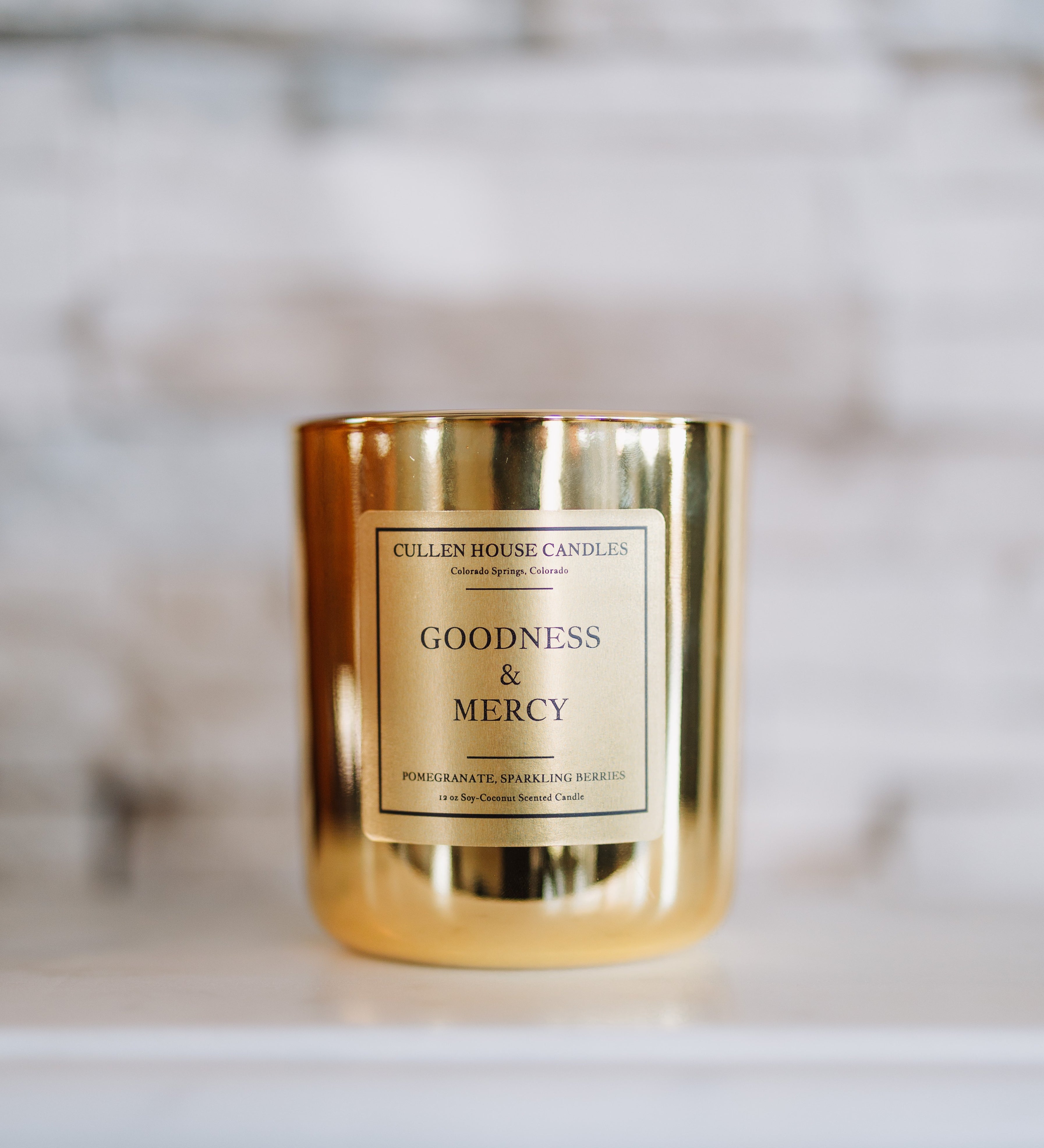 Gold candle with 'Goodness & Mercy' label on a marble surface