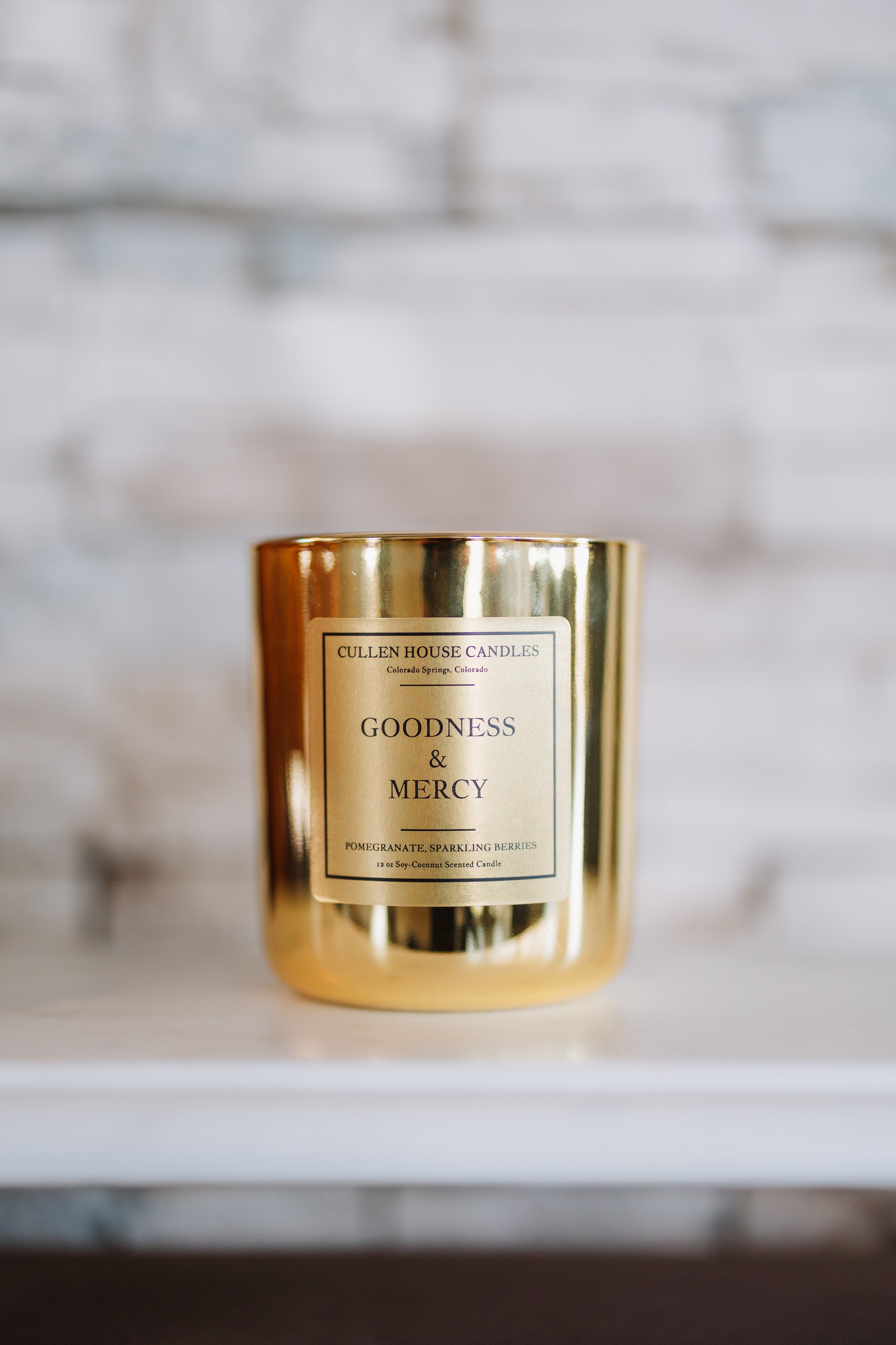 Gold candle with 'Goodness & Mercy' label on a marble surface