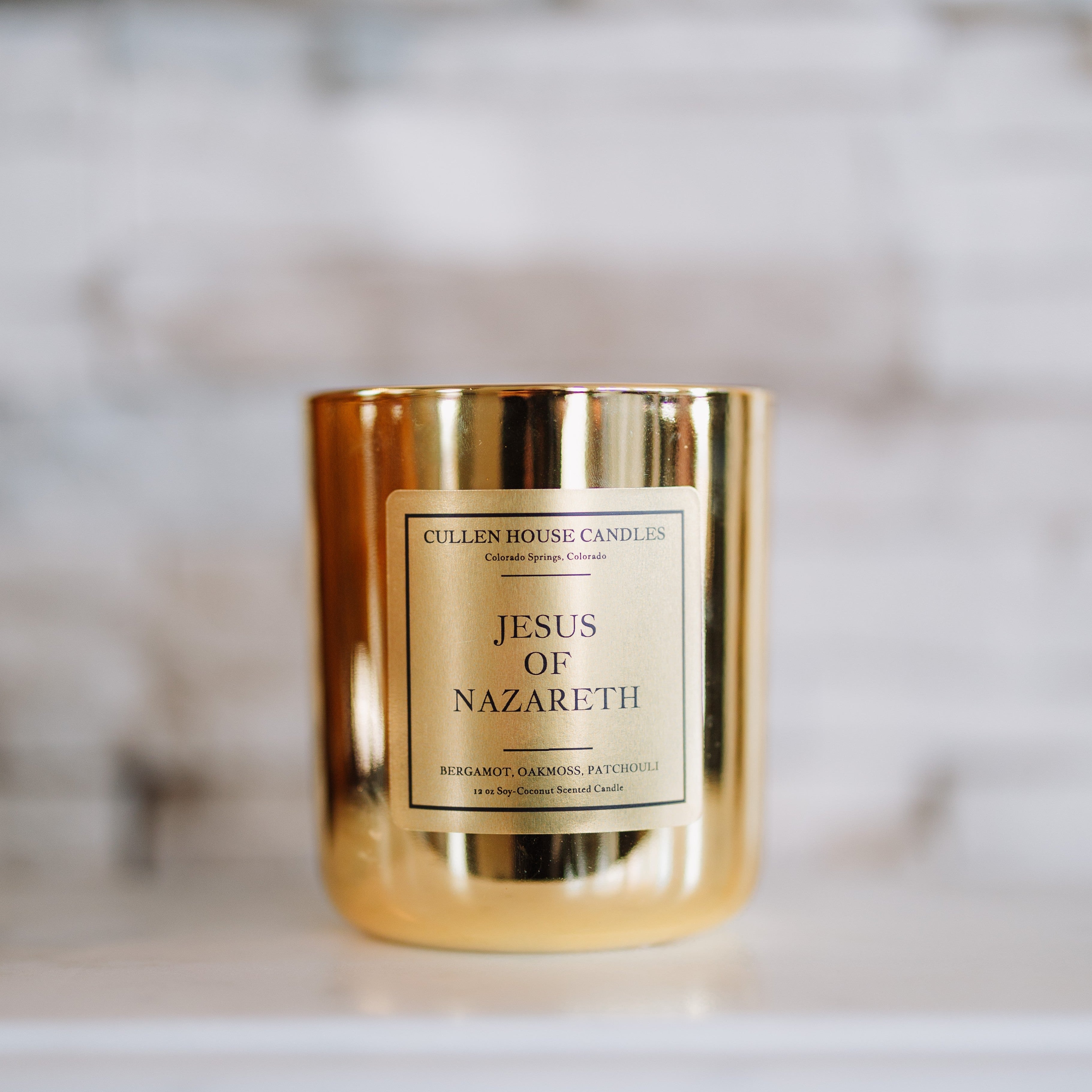 Gold candle with 'Jesus of Nazareth' label on a blurred background