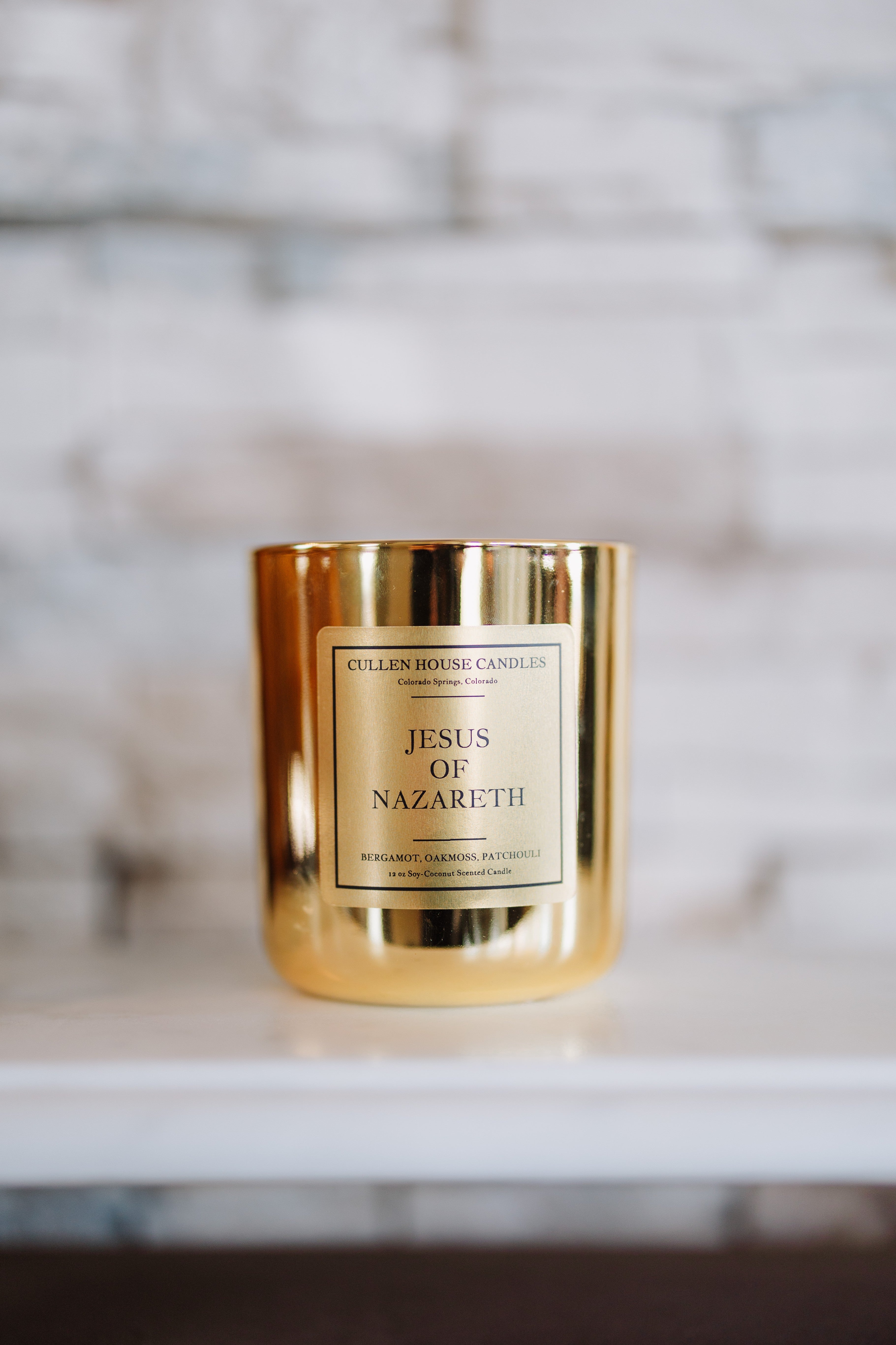 Gold candle with 'Jesus of Nazareth' label on a blurred background