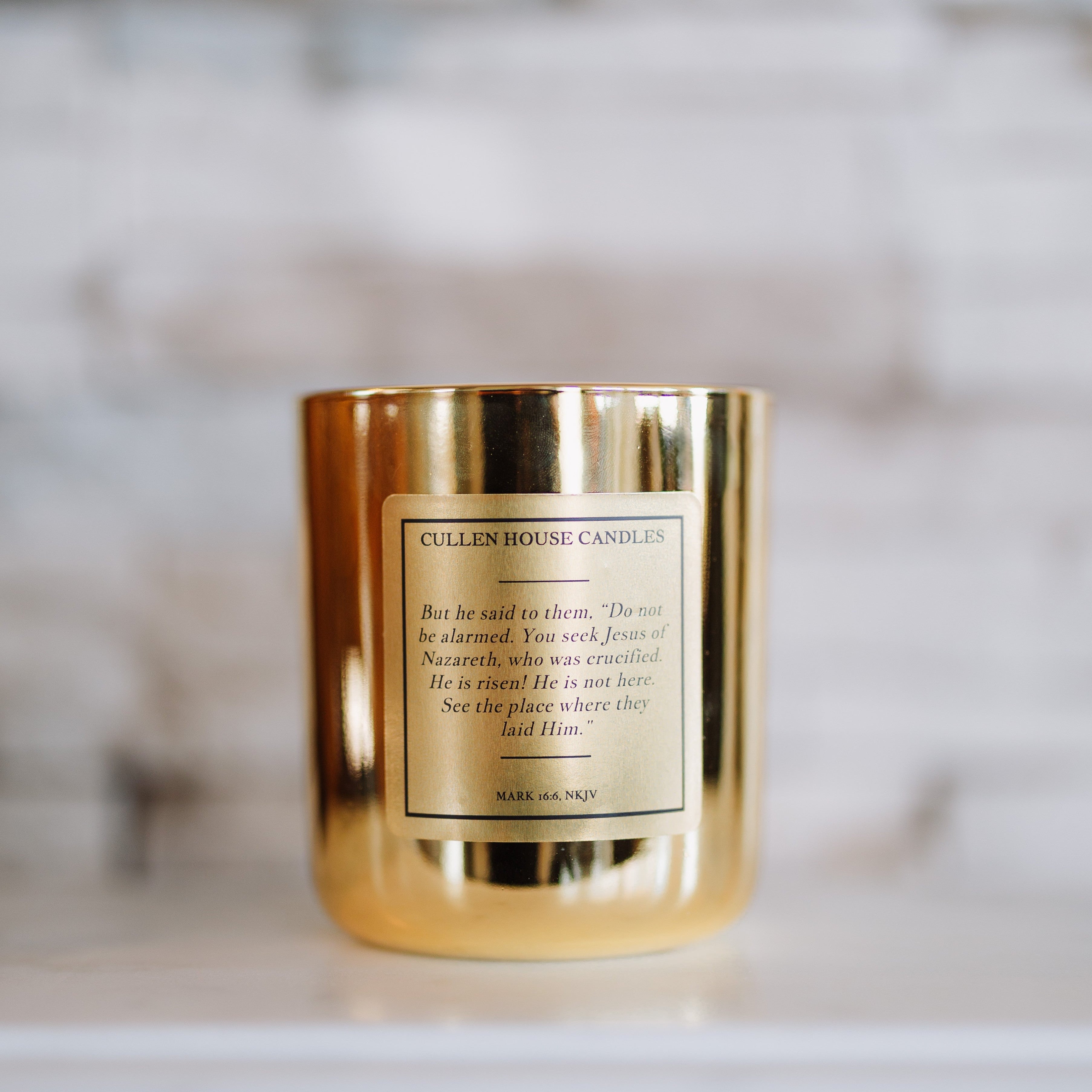 Gold candle with a label on a marble surface