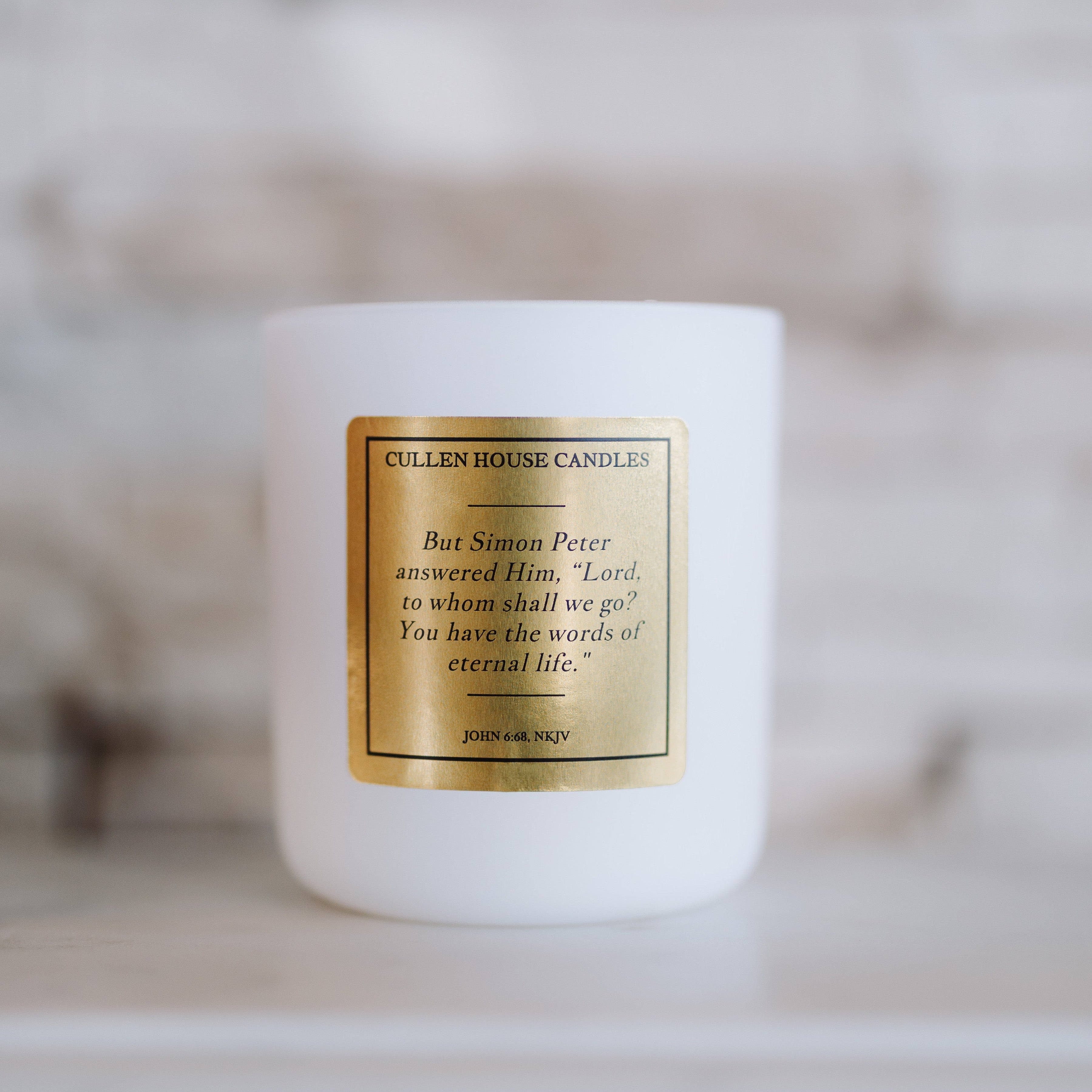 White candle with a gold label on a blurred background