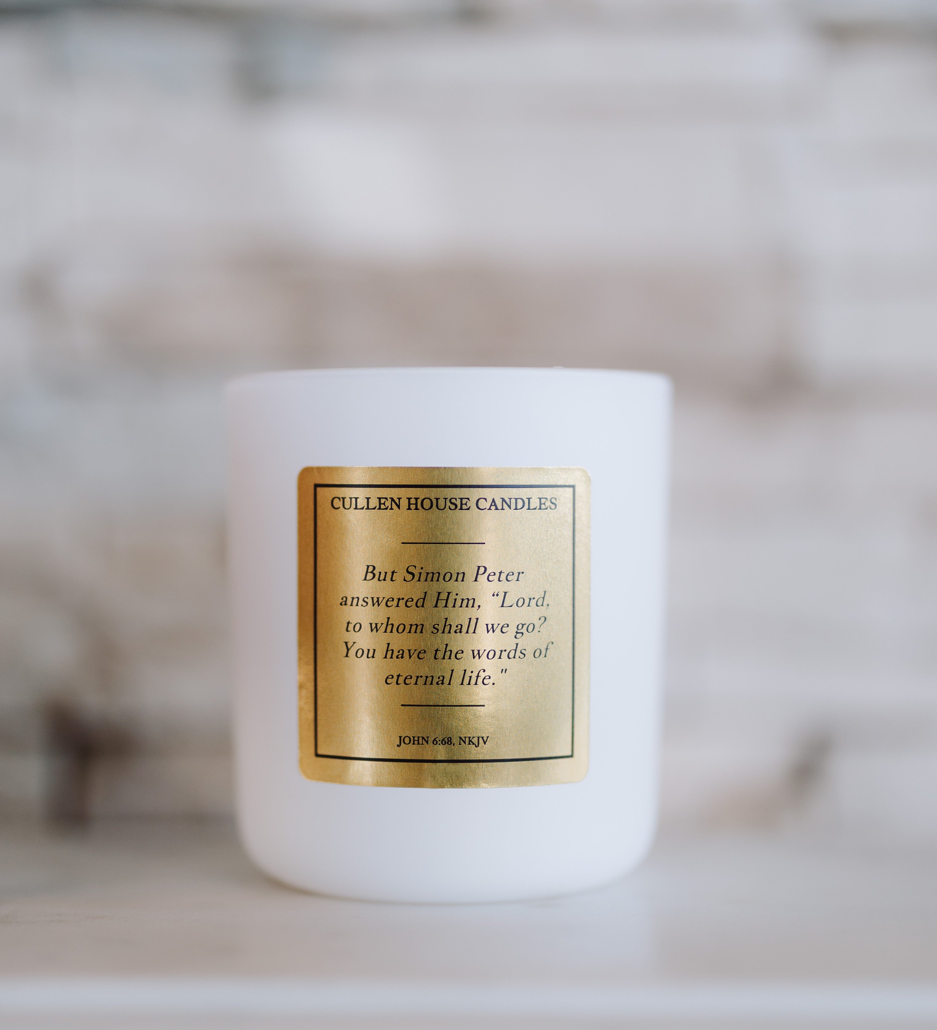 White candle with a gold label on a blurred background