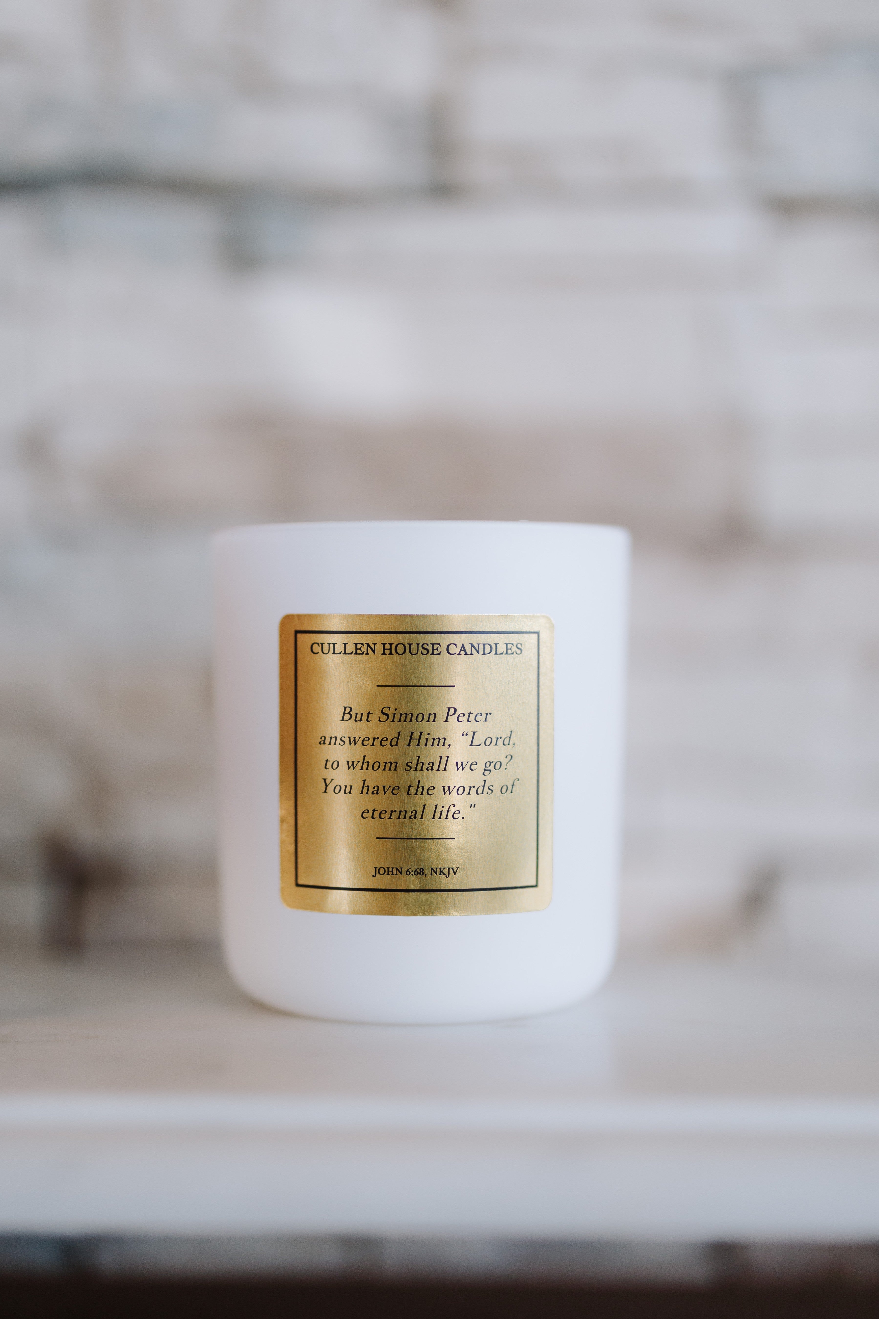 White candle with a gold label on a blurred background