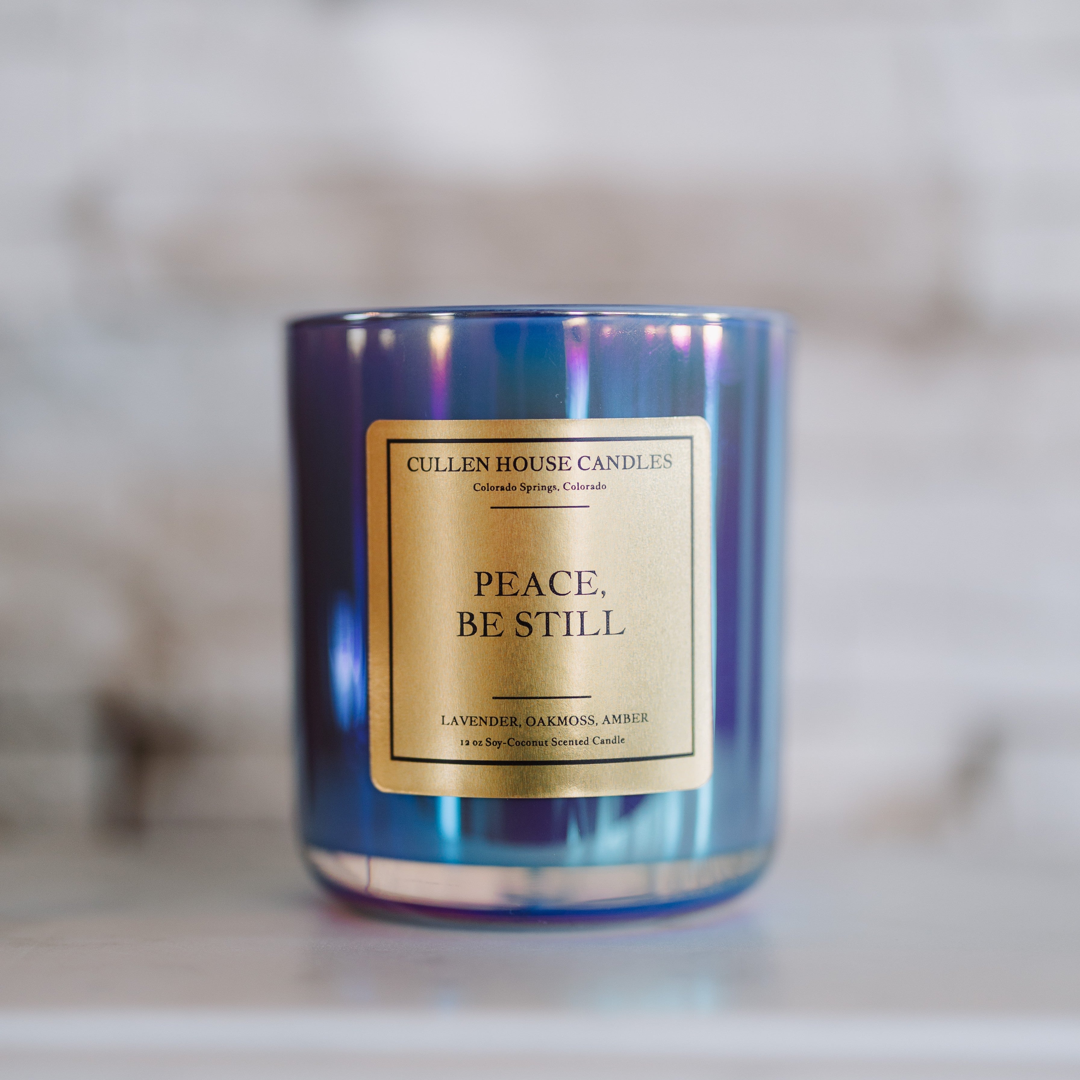 Candle with 'Peace. Be Still' label on a marble surface