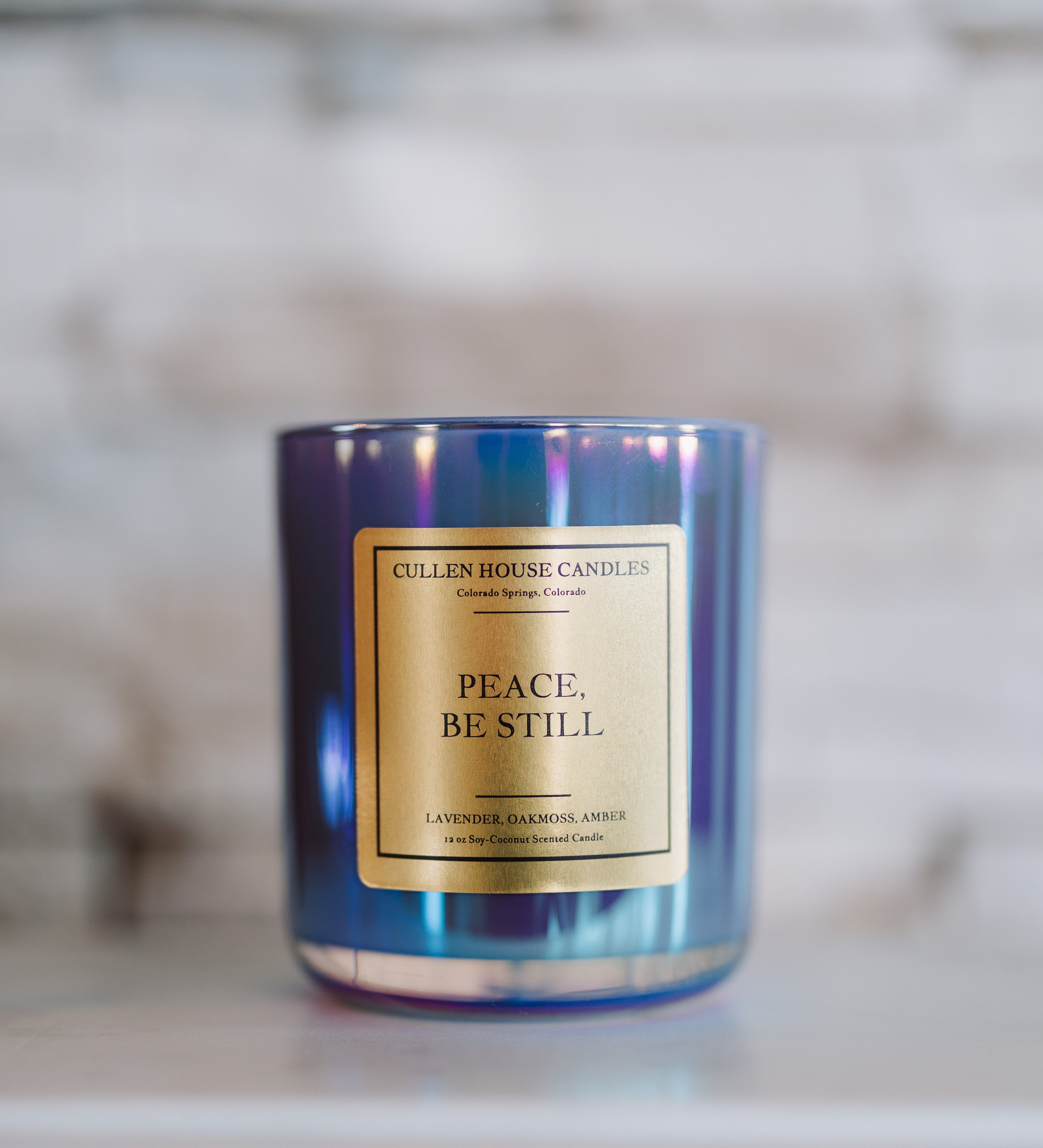Candle with 'Peace. Be Still' label on a marble surface