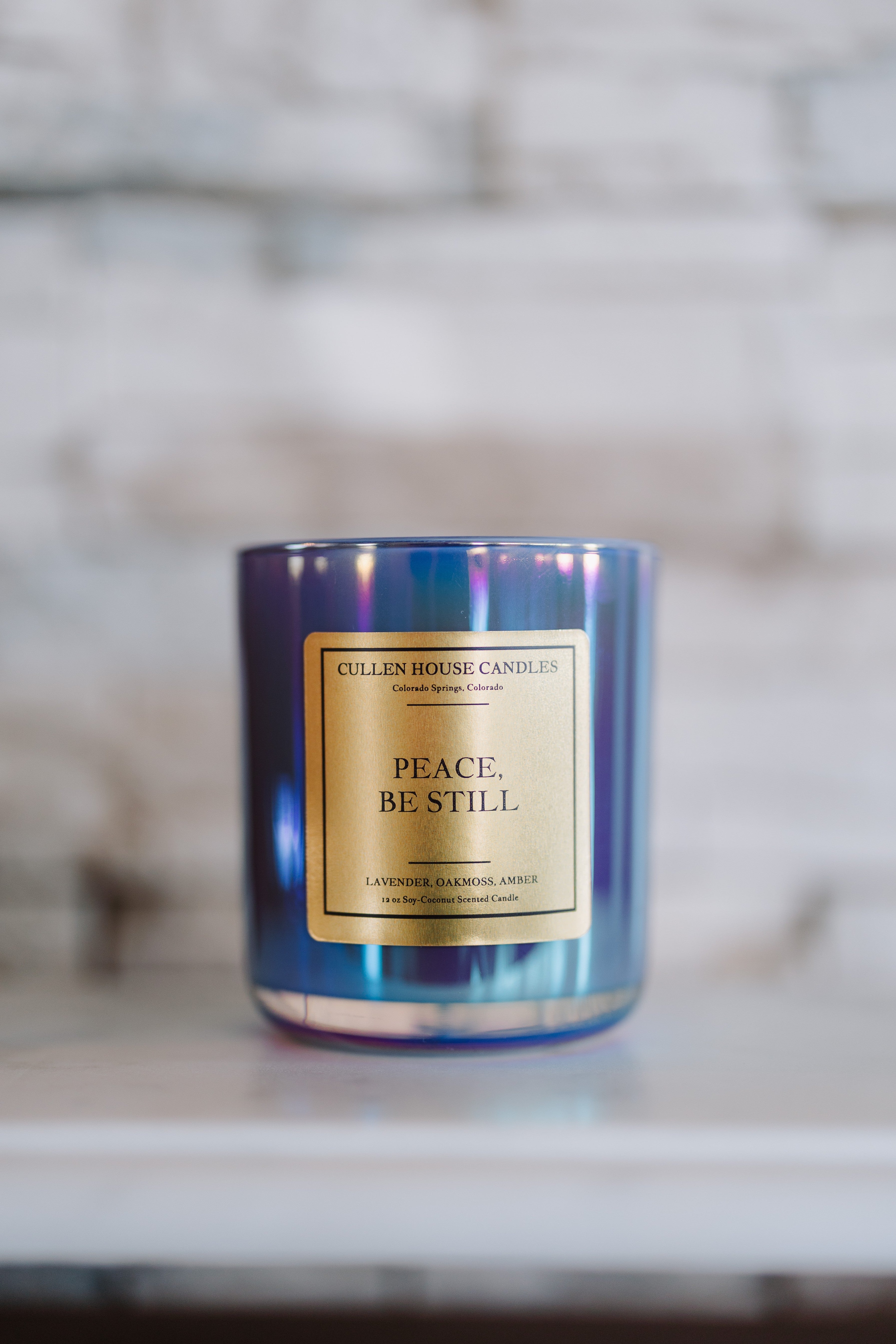 Candle with 'Peace. Be Still' label on a marble surface