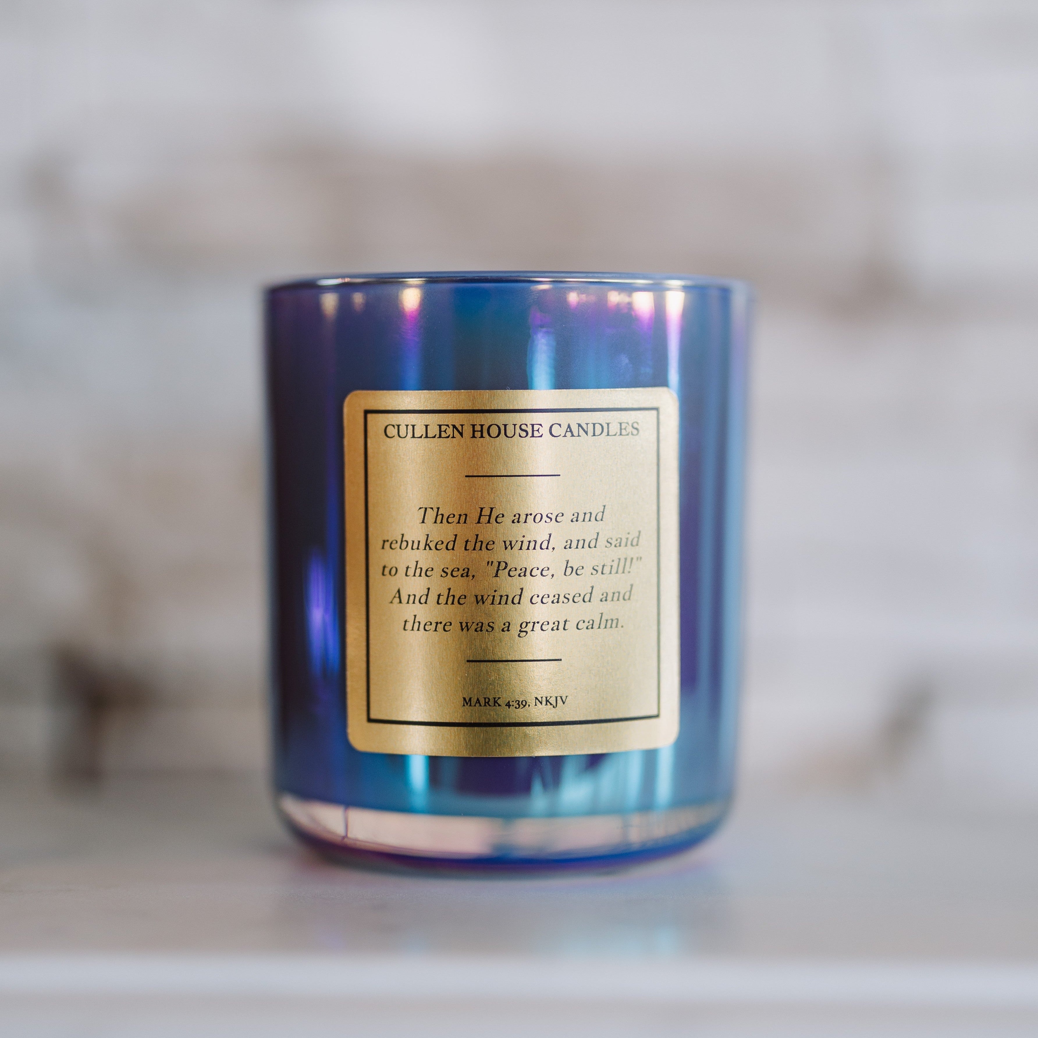 Blue candle with a gold label on a marble surface