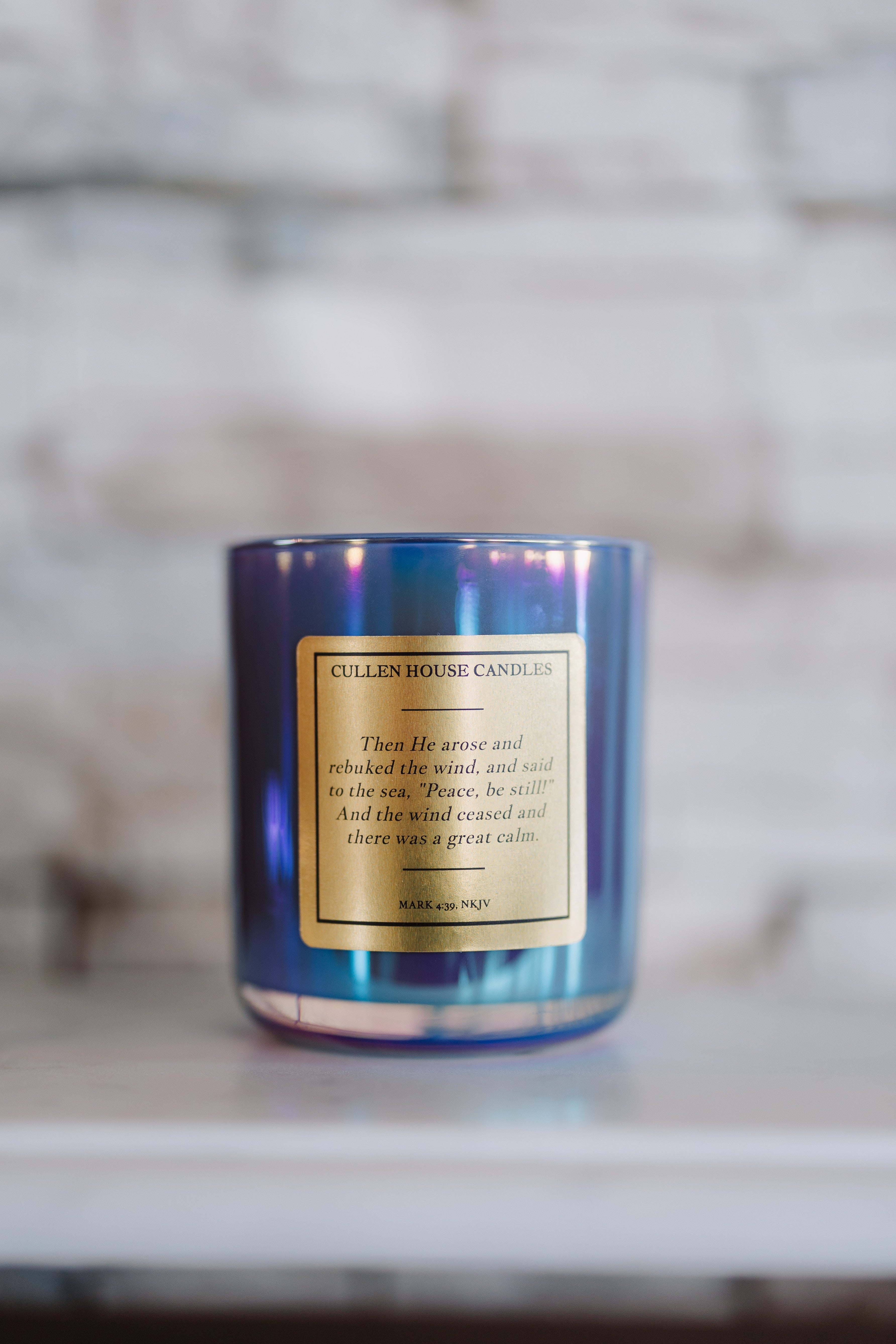 Blue candle with a gold label on a marble surface