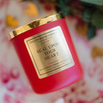 Red candle with a gold lid and label on a floral background