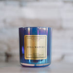 Candle with a blue tinge and gold label on a blurred background